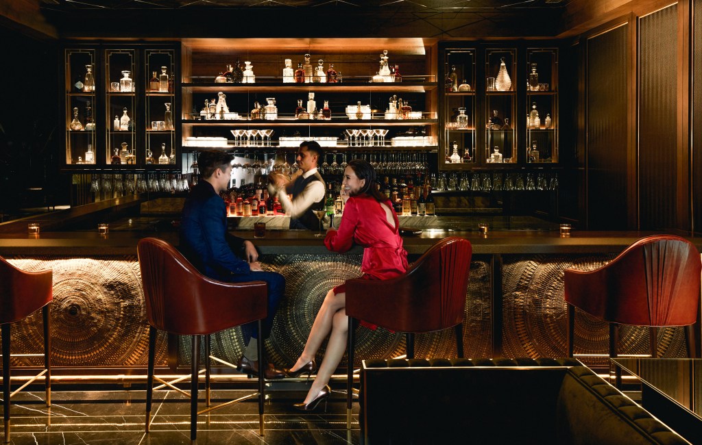 Couple sitting at bar while bartender makes drinks