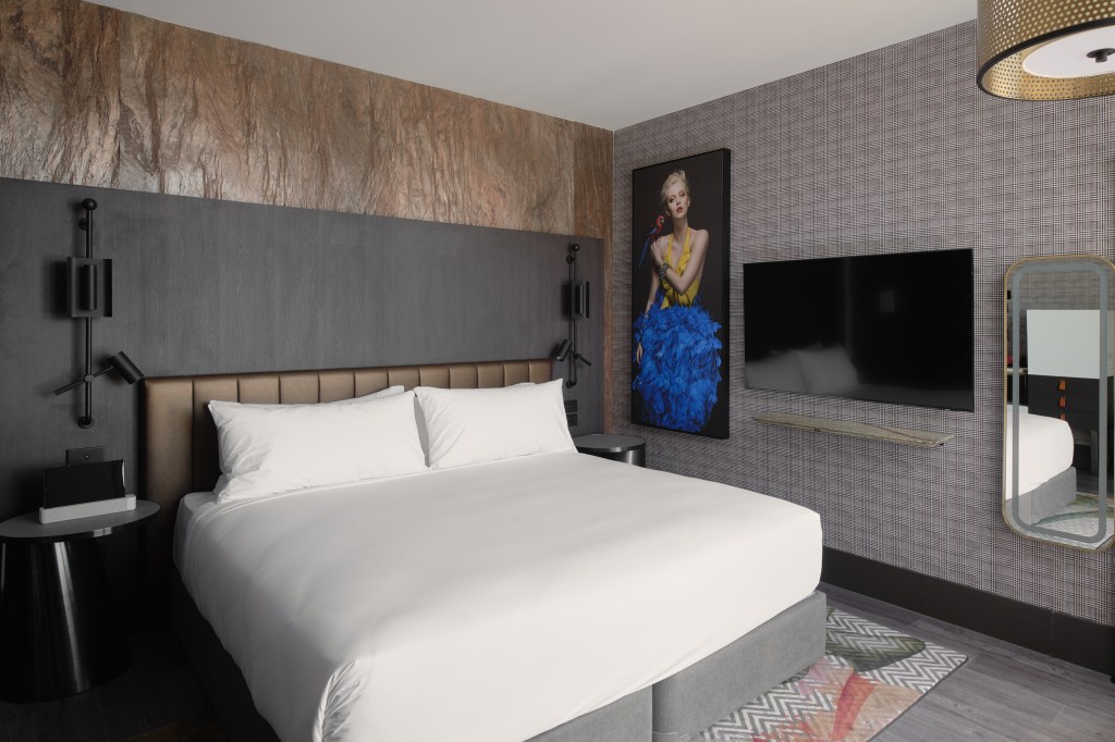 The Motley Hotel Richmond, Tapestry Collection by Hilton - Guest Room with white bedding and grey and gold accents, and colorful artwork