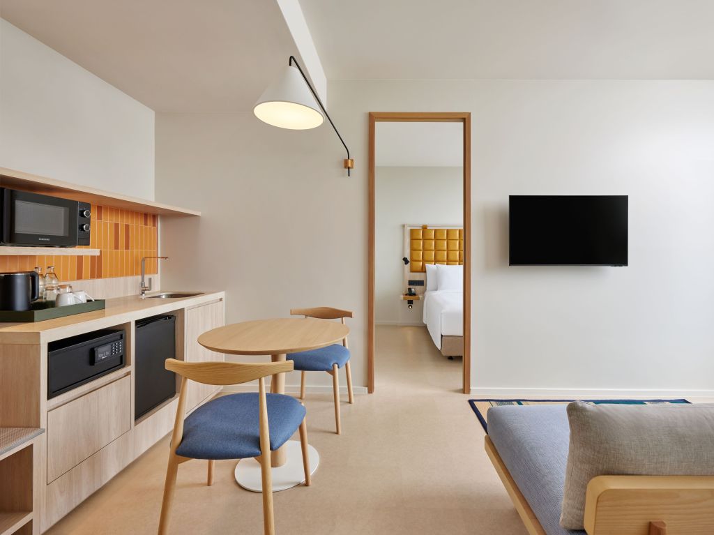 kitchen, table and chairs, seating and television, and doorway looking into bedroom in King Deluxe Suite at Hilton Garden Inn Rayong