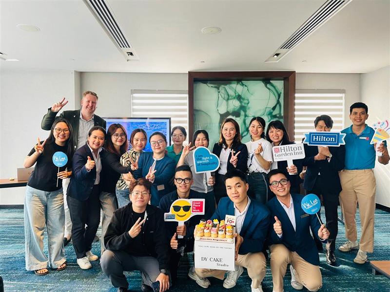 Hilton Named #1 Best Workplace in Vietnam- Hilton Garden Inn Da Nang group photo of team members posing with signs and cupcakes