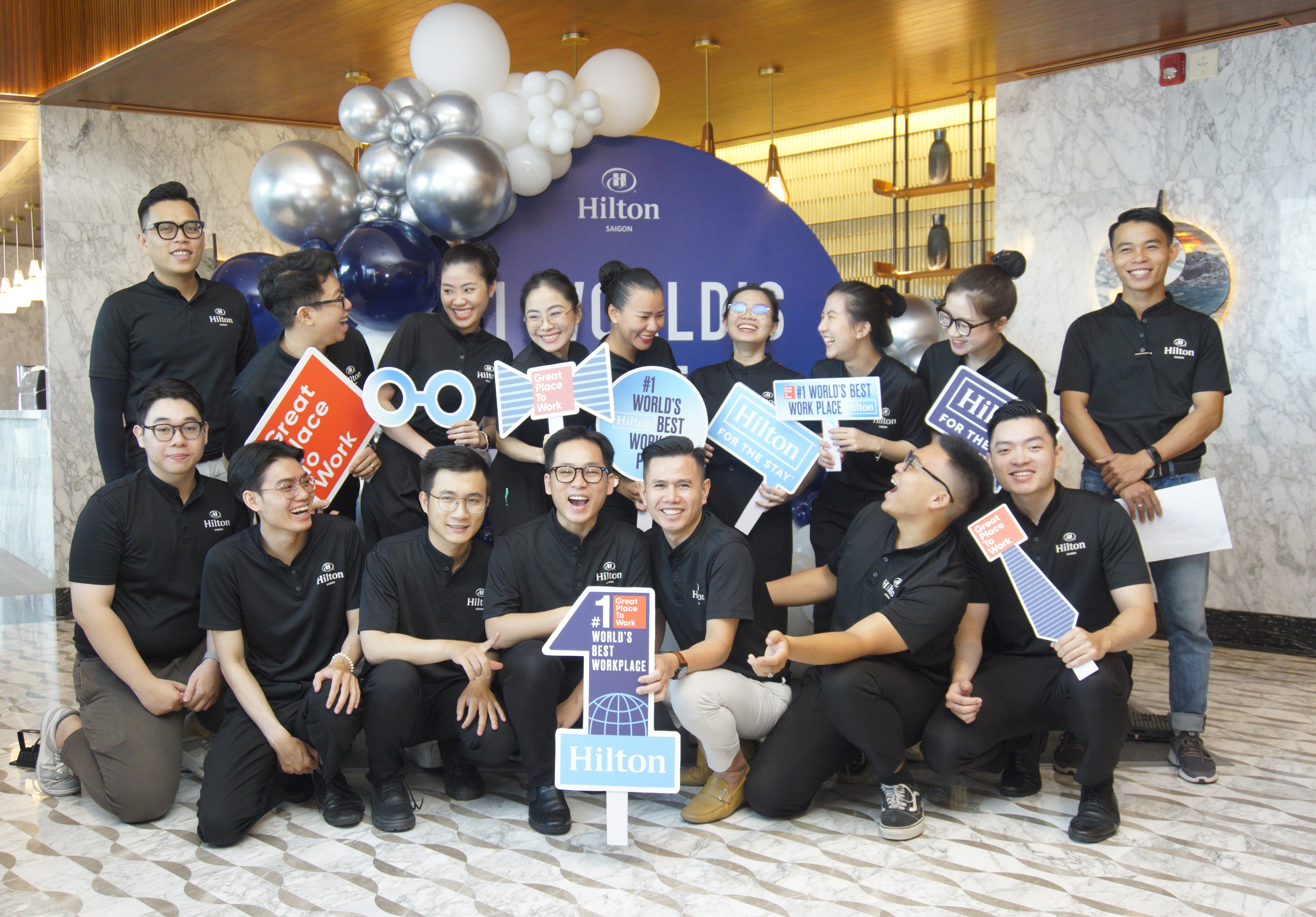 Hilton Named #1 Best Workplace in Vietnam - Hilton Saigon - group photo of team members with Great Place to Work signs posing in front of a backdrop with balloons