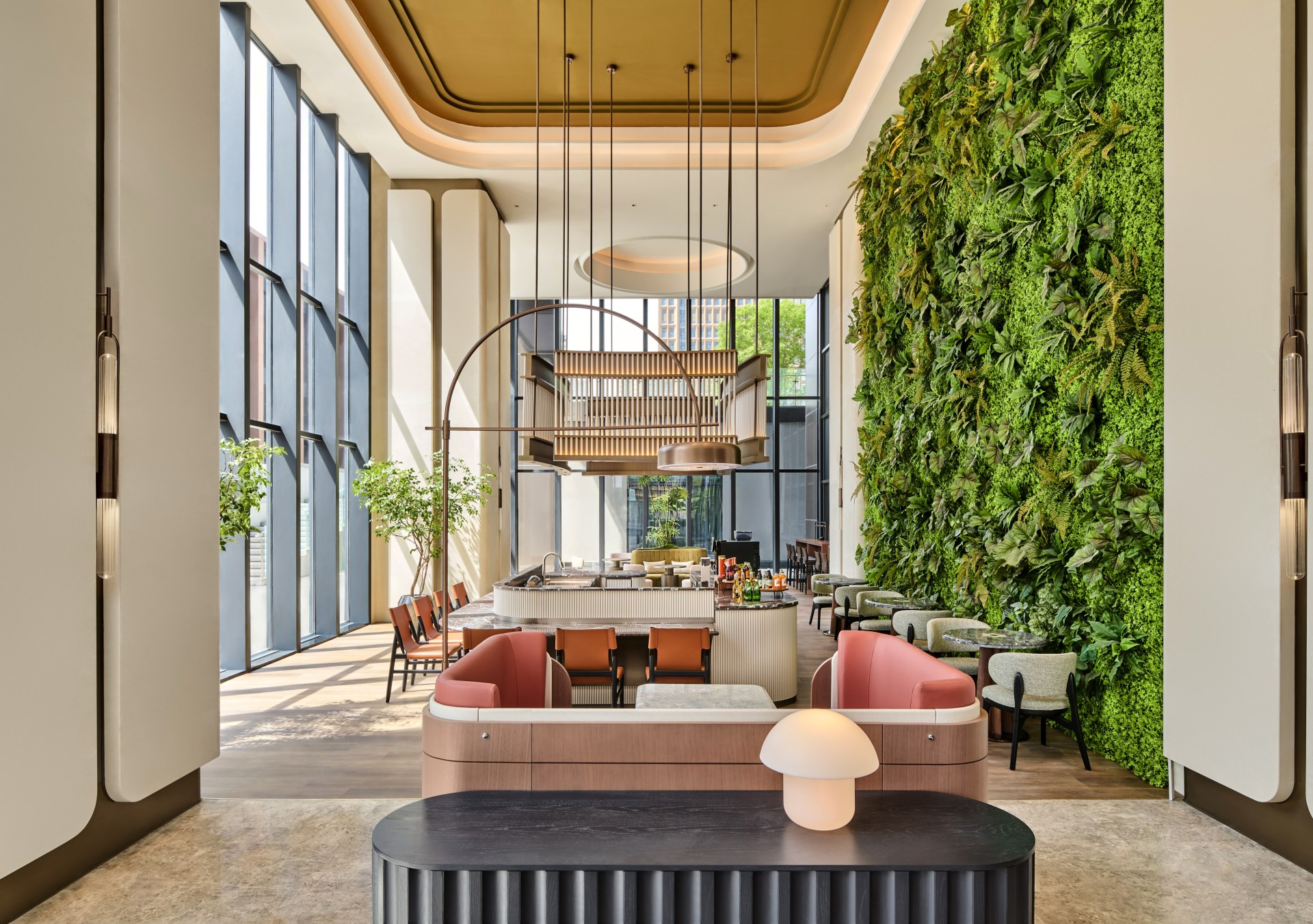 Hilton Garden Inn Chongqing Yubei Central Park Lobby with tables and chair seating area around a cafe bar with a living plant wall on one side of the room and floor to ceiling windows on the opposite side of the room