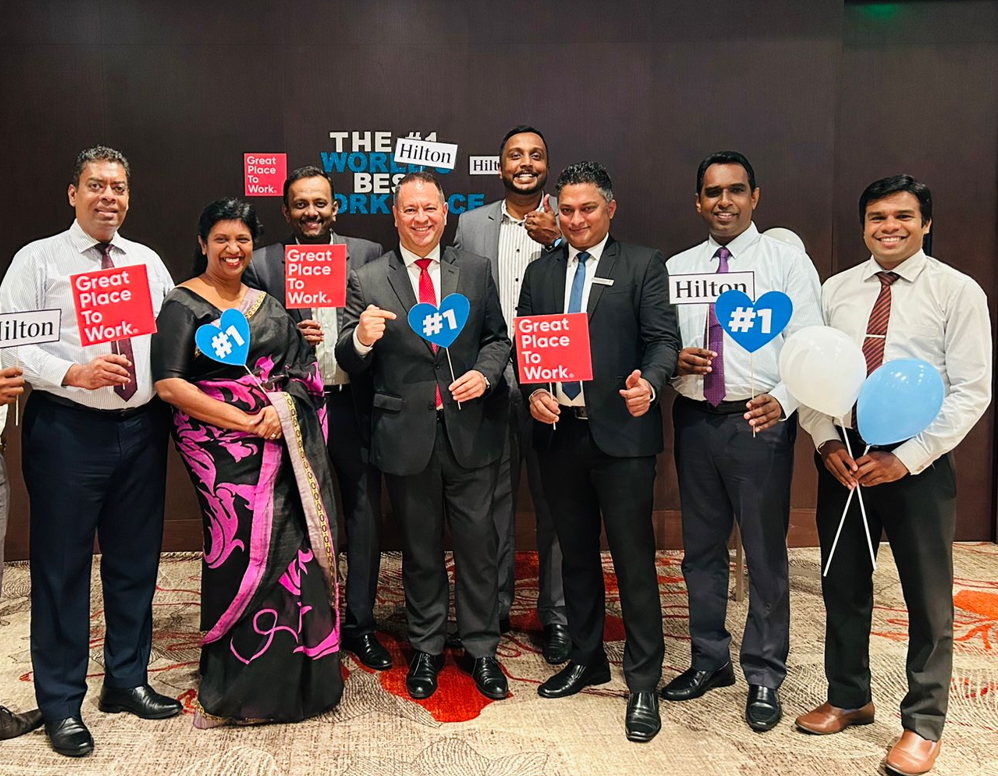 group of eight Hilton Colombo Residences Team Members holding Great Place to Work signs