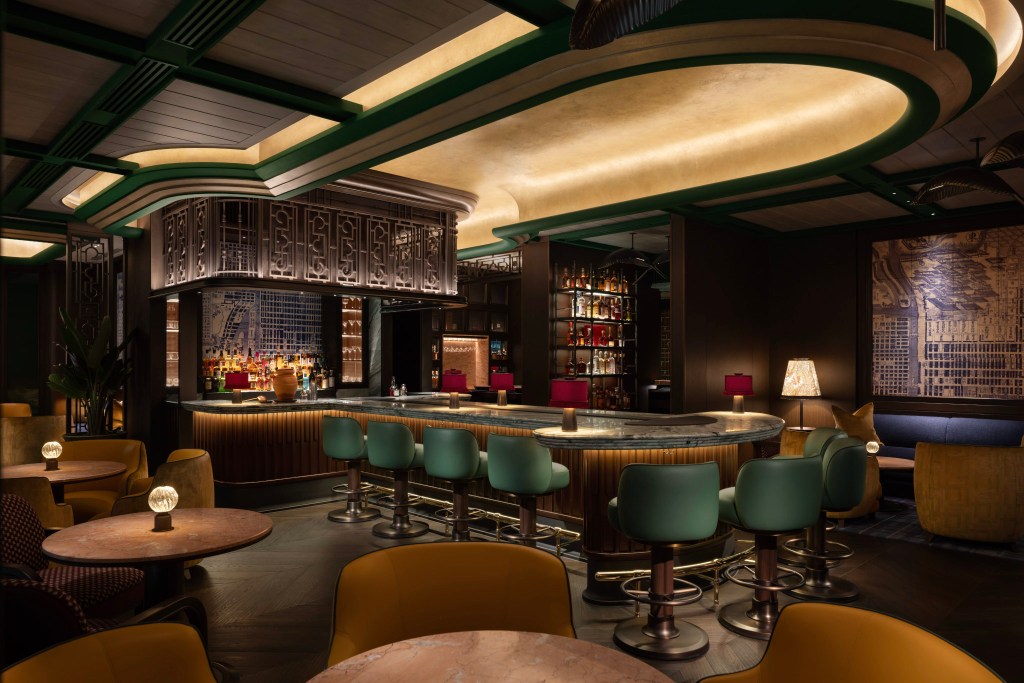 Luxurious hotel bar with a curved marble counter, art deco details, plush seating, and warm ambient lighting. Canes &amp; Tales, Waldorf Astoria Osaka. Hilton