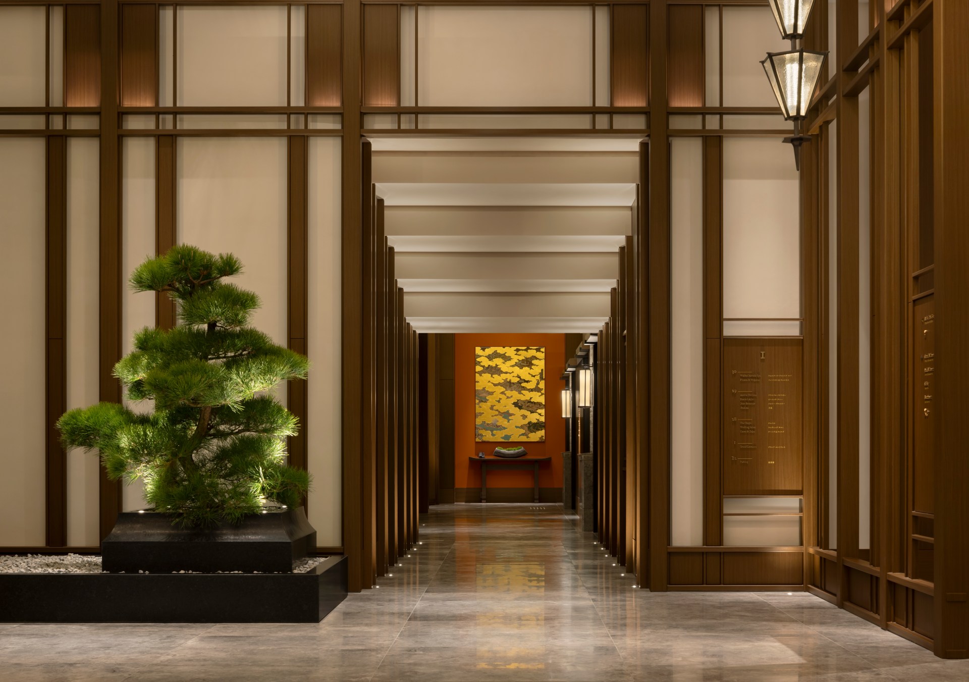 Waldorf Astoria Osaka Lobby area with large bonsai tree, and decorative art at the end of a hall way