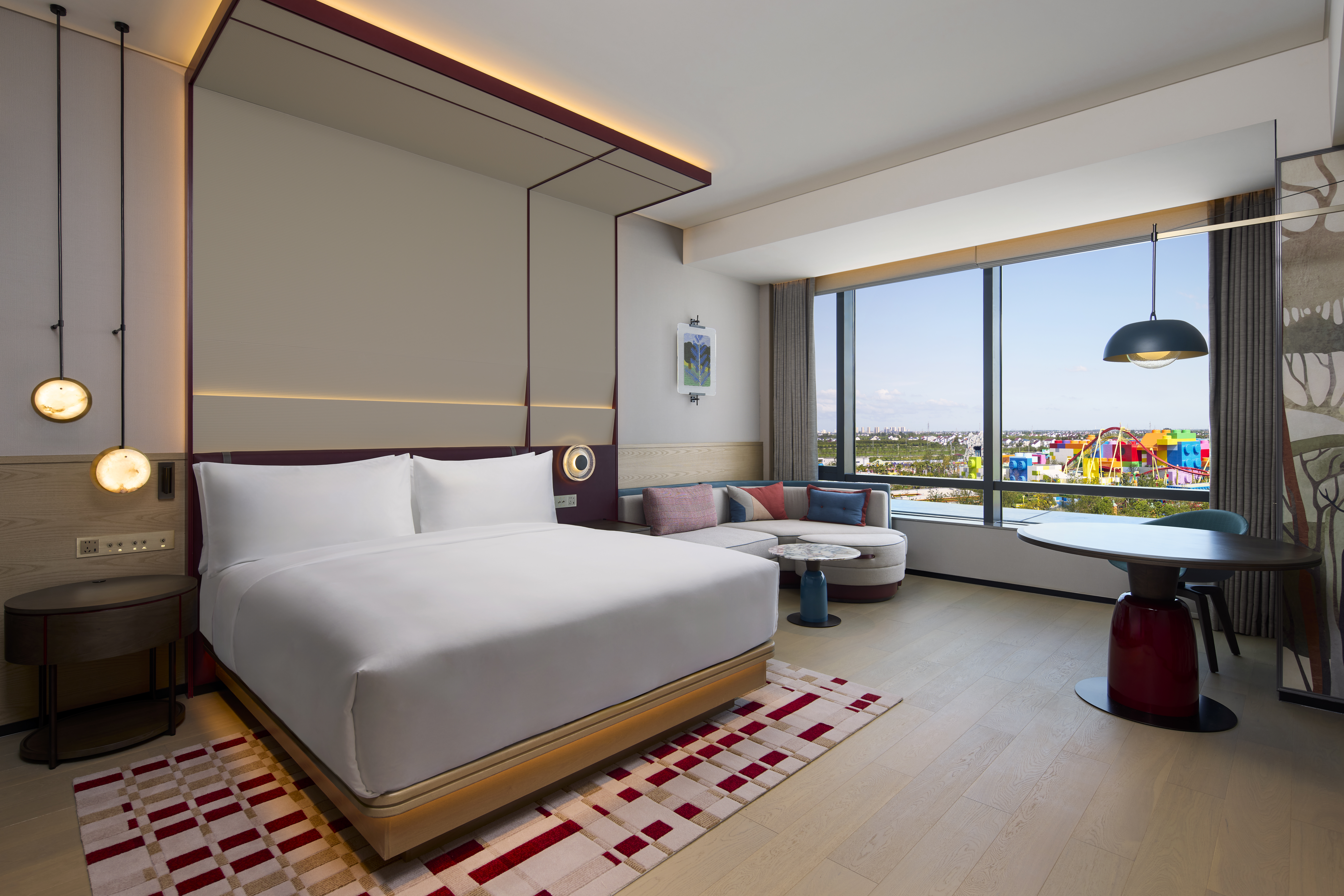 A room with bed, couch seating area, dining table, and a view of LEGOLAND