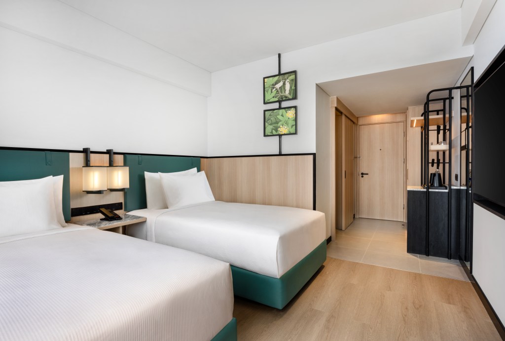 A room with 2 twin beds, tv, and wardrobe.