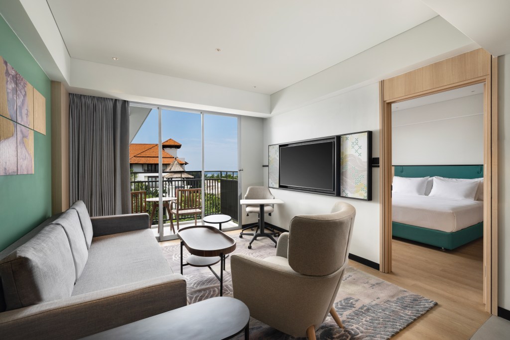 A living area in the King Deluxe Suite with couch and chairs, overlooking a balcony.