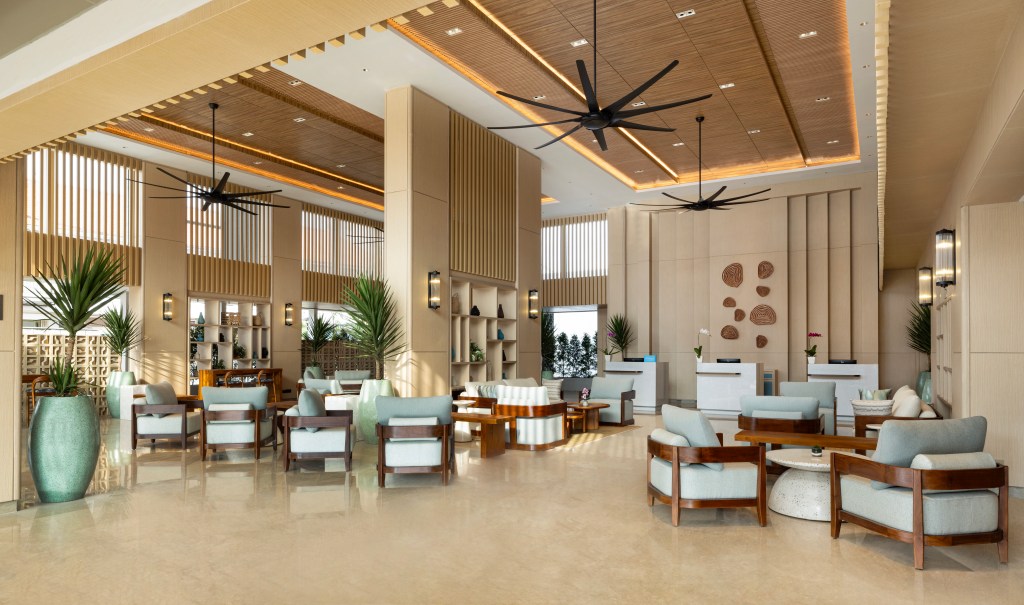 The bright and warm lobby of the Hilton Garden Inn Bali Nusa Dua with various seating areas.