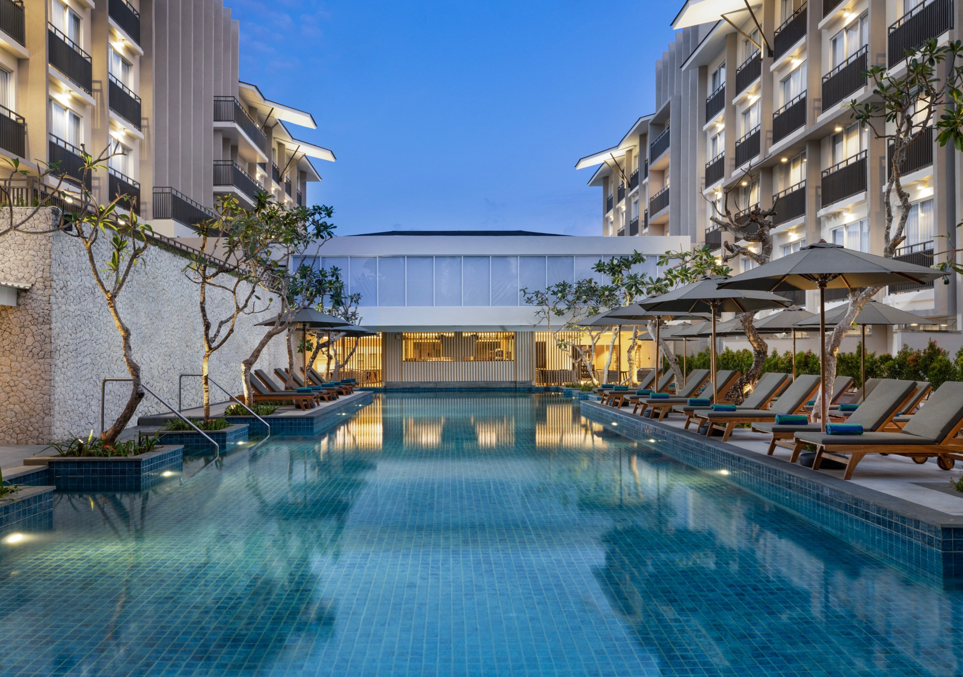 An evening view of the pool with lounge chairs and umbrellas