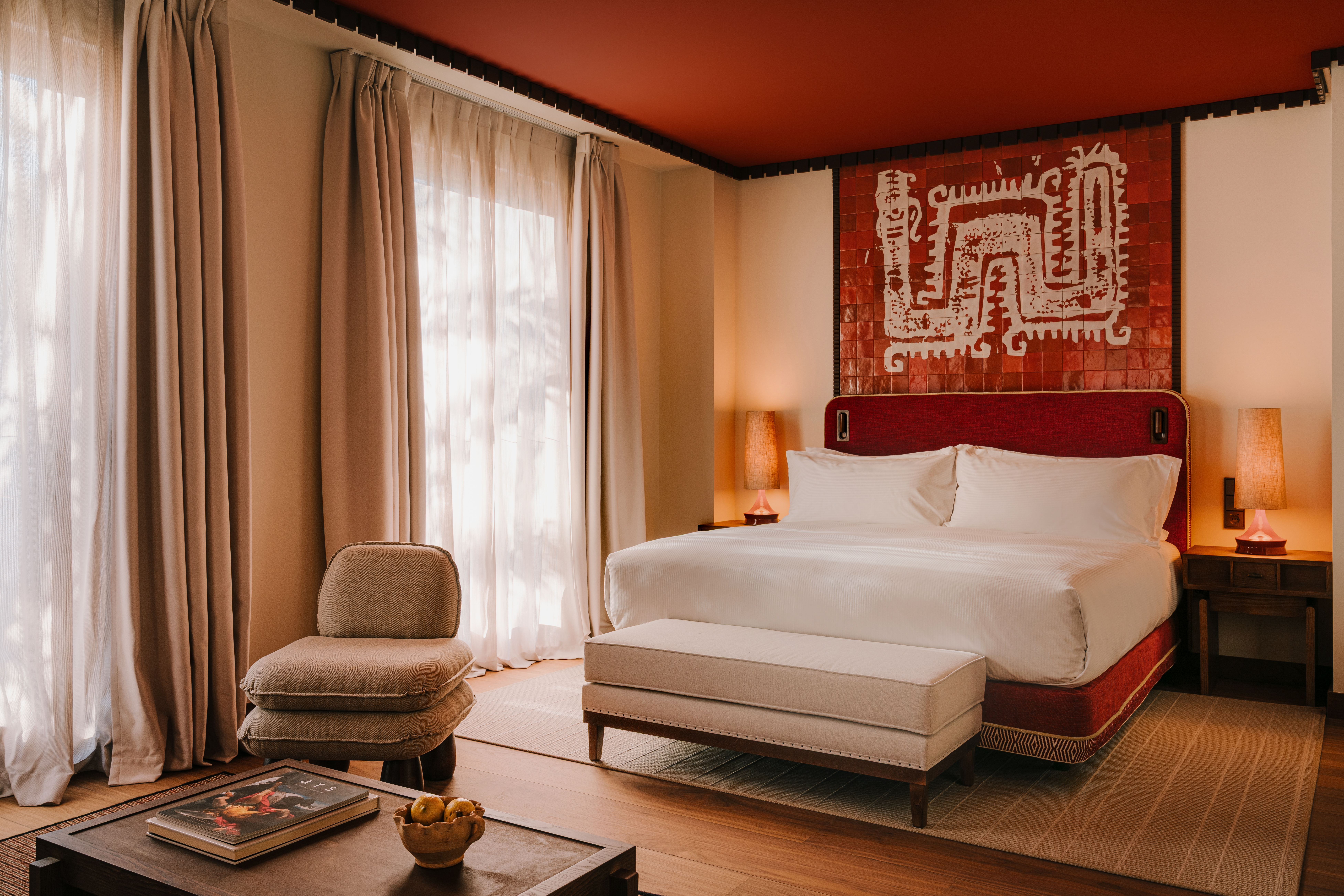 A bedroom with a bed, bench, and a seating area.