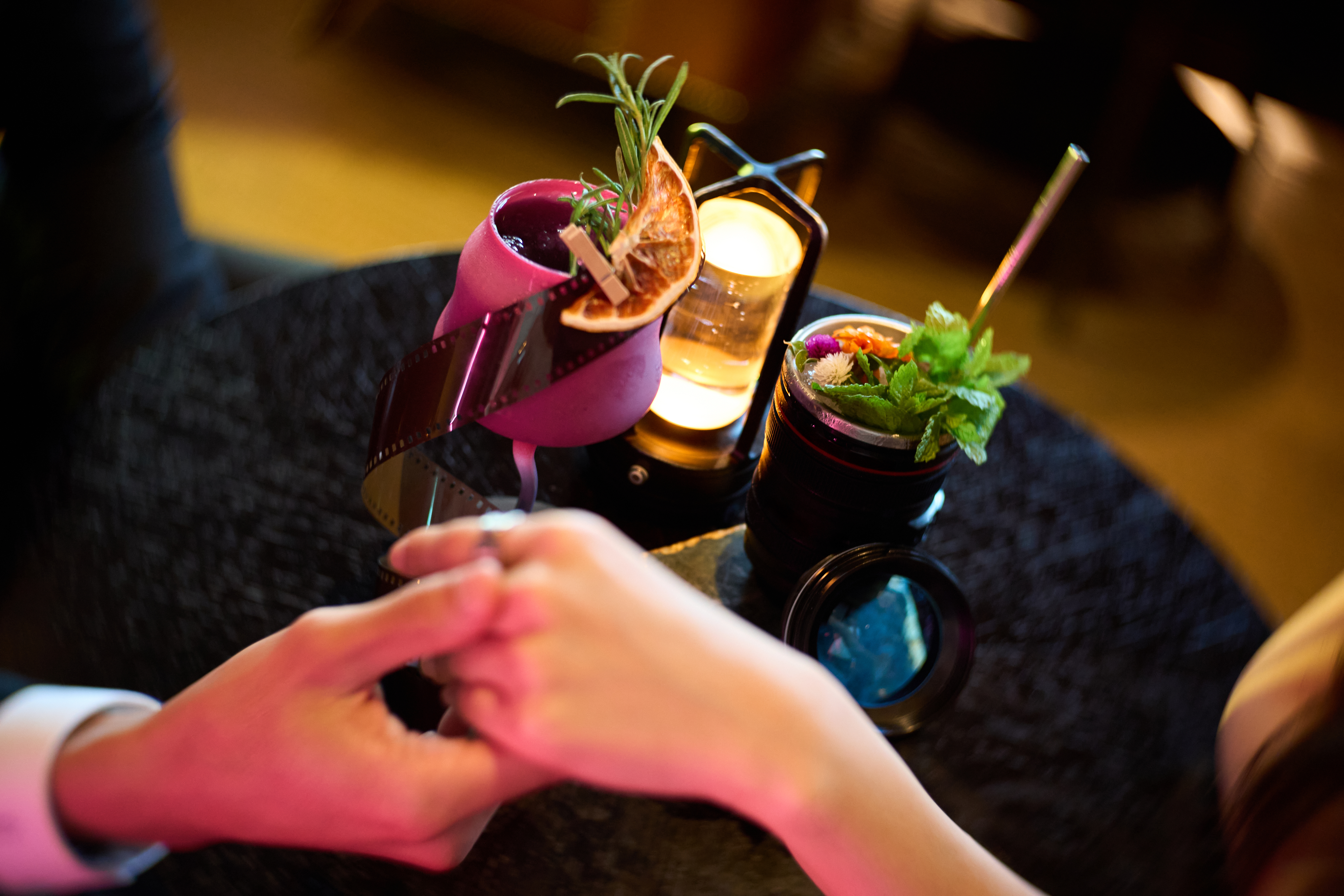 A couple holding hands over cocktails