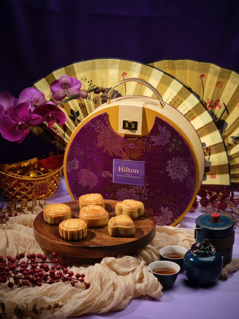 Mooncakes on a platter in front of a round box with a purple floral lid
