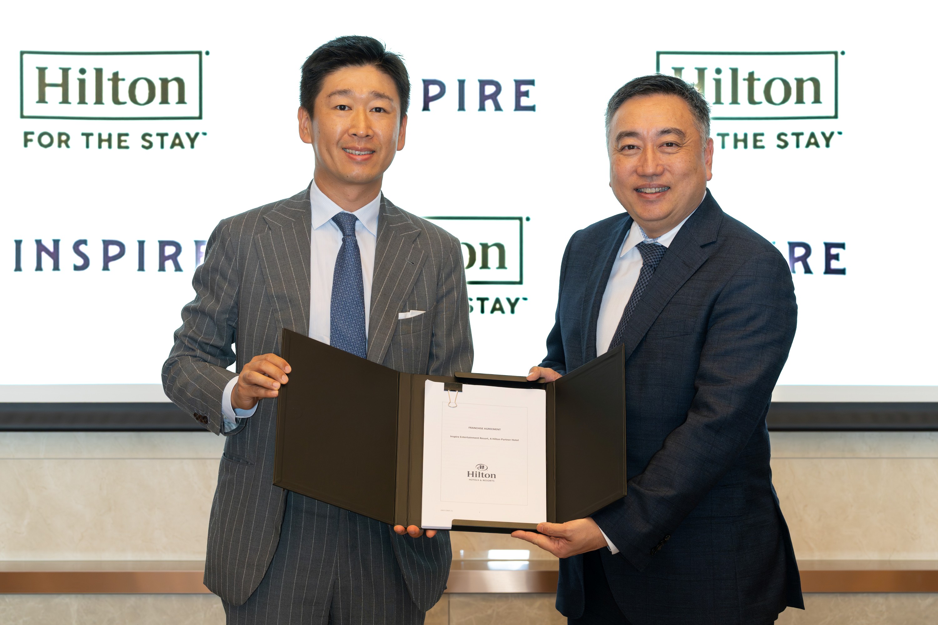 two men holding a document smiling at camera