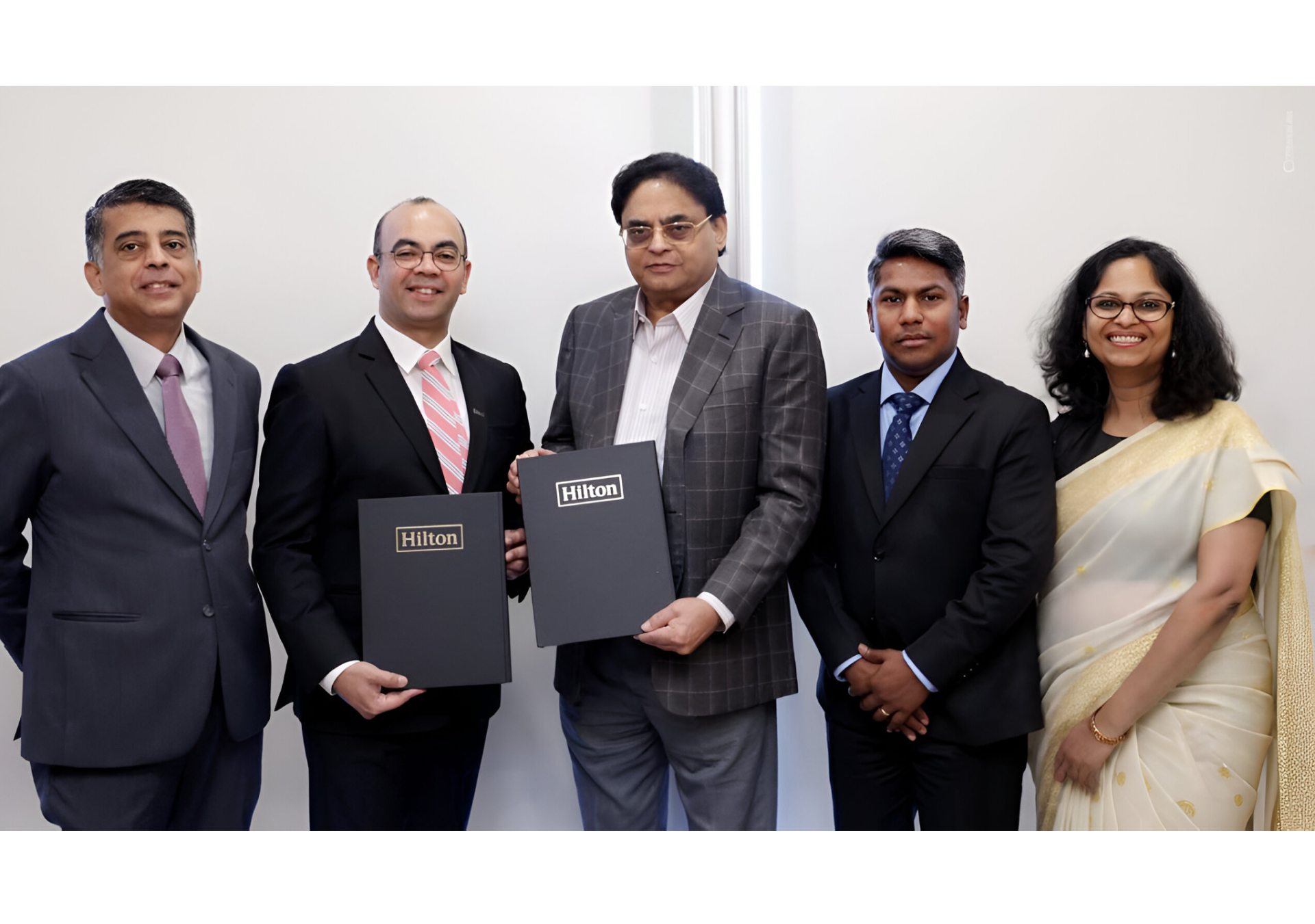 A group of executives hold documents and smile at camera