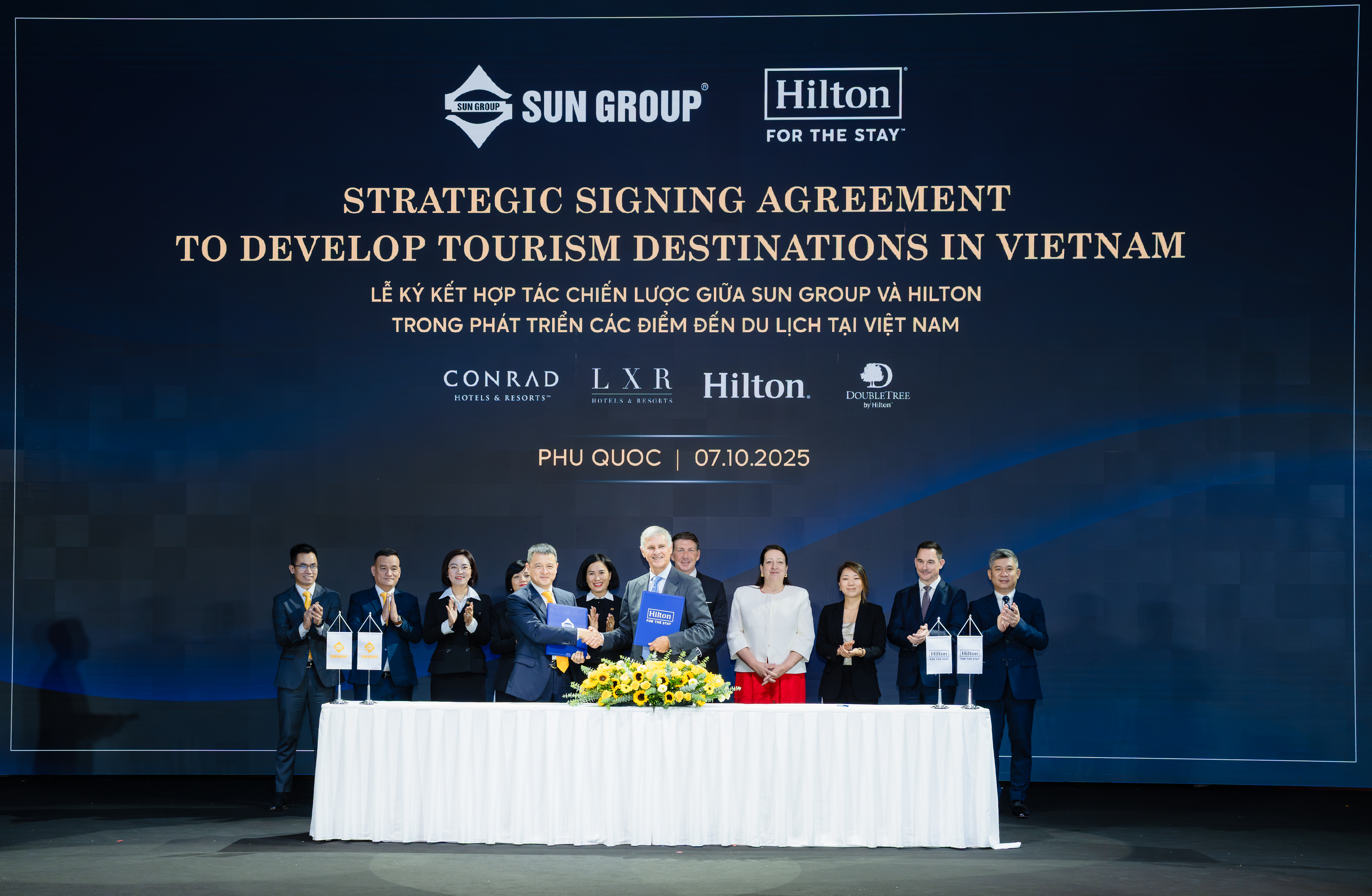 A group of Sun Group and Hilton leaders smiling at camera at the signing of the agreement.