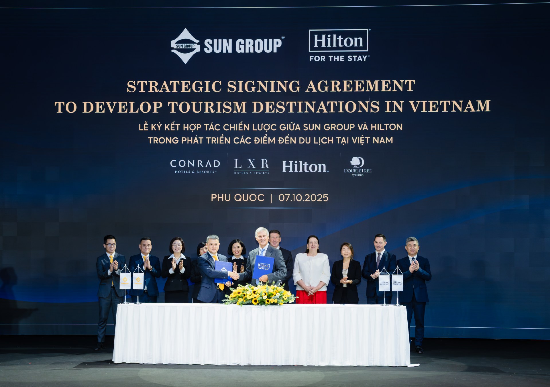 A group of Sun Group and Hilton leaders smiling at camera at the signing of the agreement.