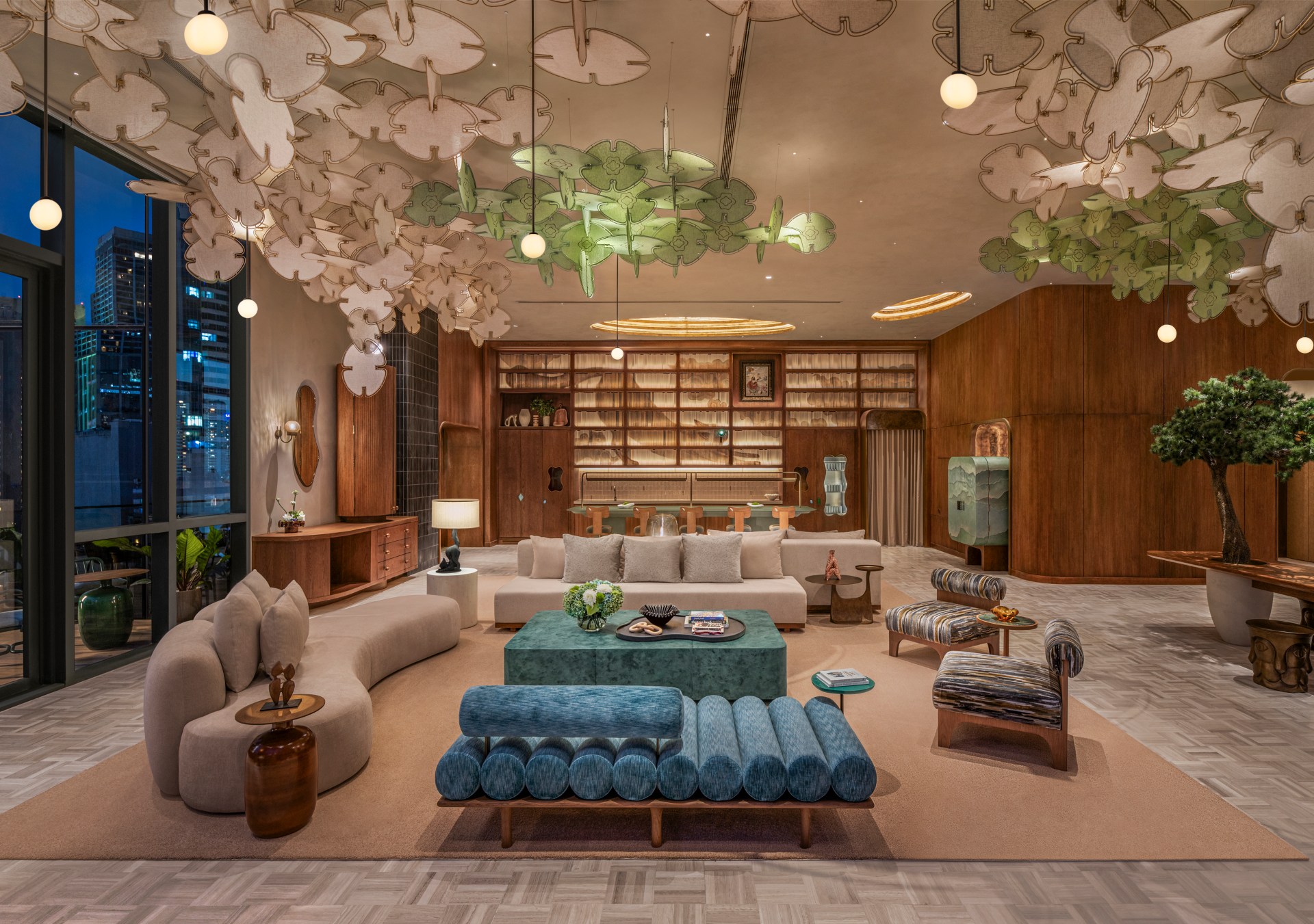 A seating area with several couches and chairs, large windows overlooking the city, and prominent sculpture hanging from the ceiling.