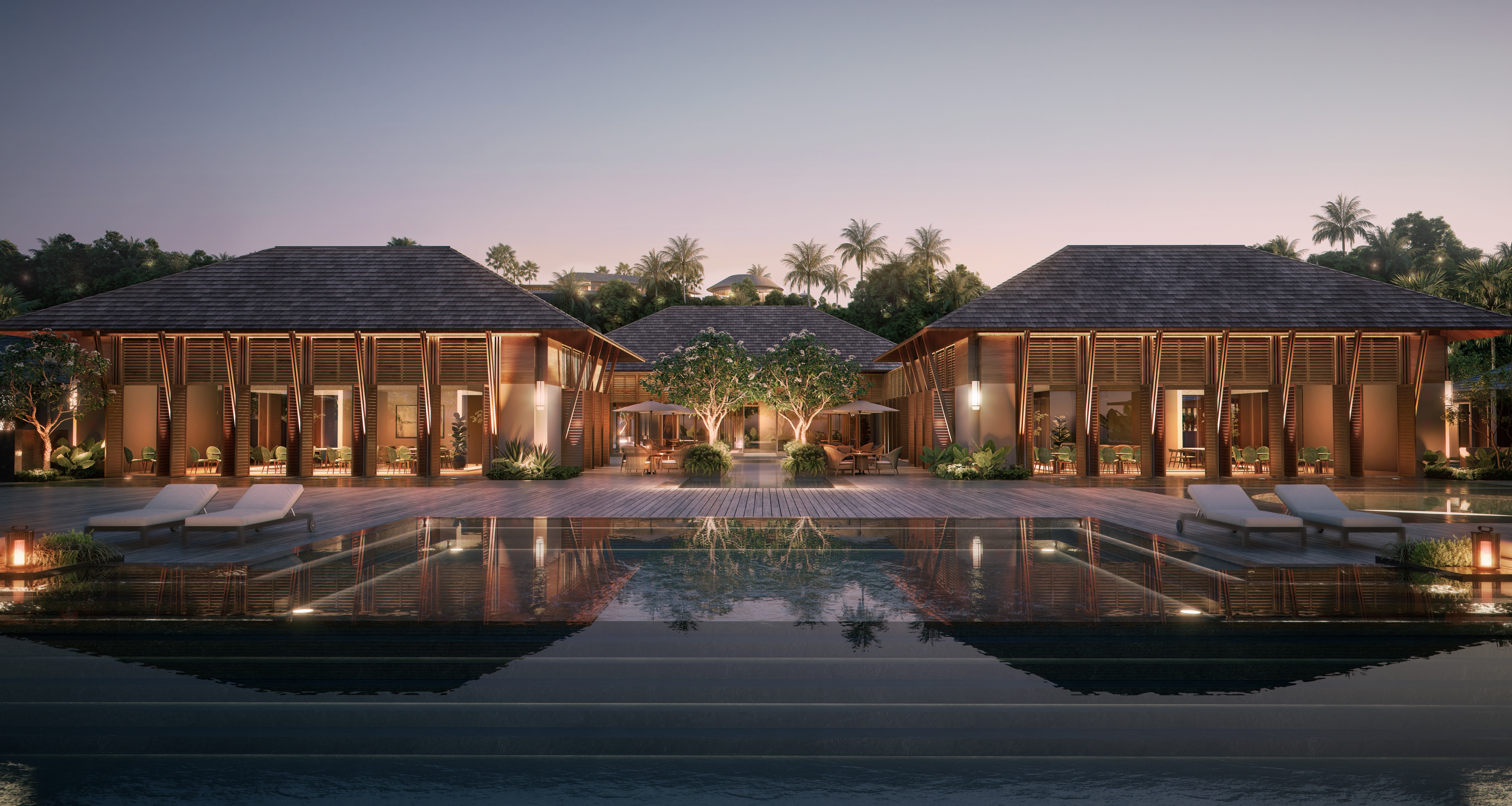 The pool of the Waldorf Astoria Bali at night with the hotel lit up behind