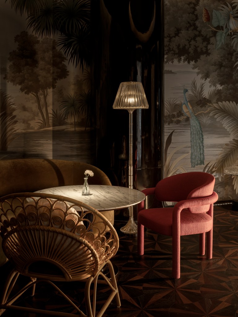 A table in the vip room surrounded by couch and chairs, in front of a peacock mural