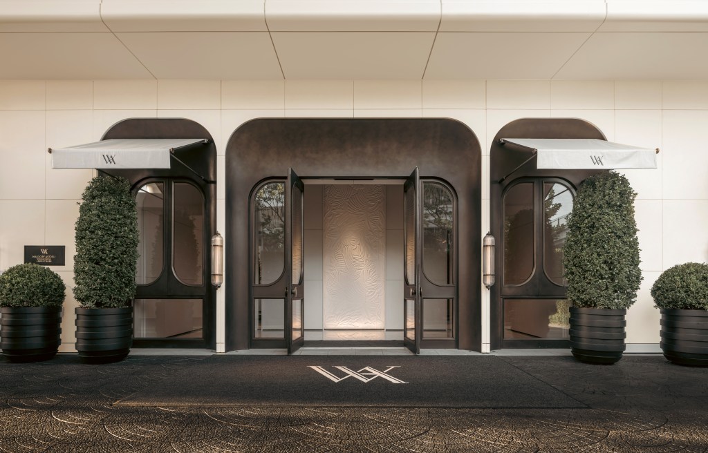 An entrance to the hotel with rounded doorways, framed by bushes