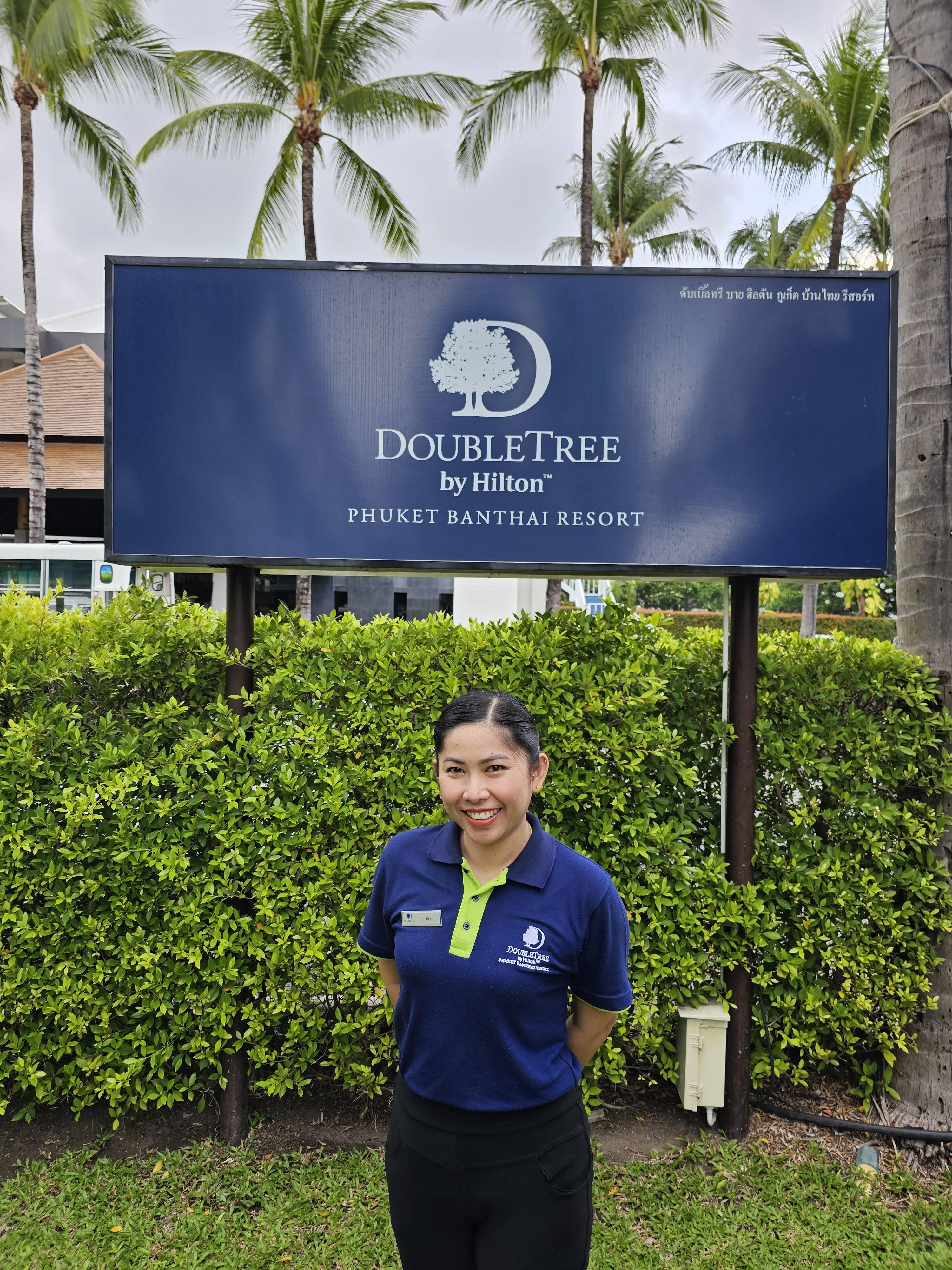 Achara Thongdee stands in front of the DoubleTree by Hilton sign and smiles at camera