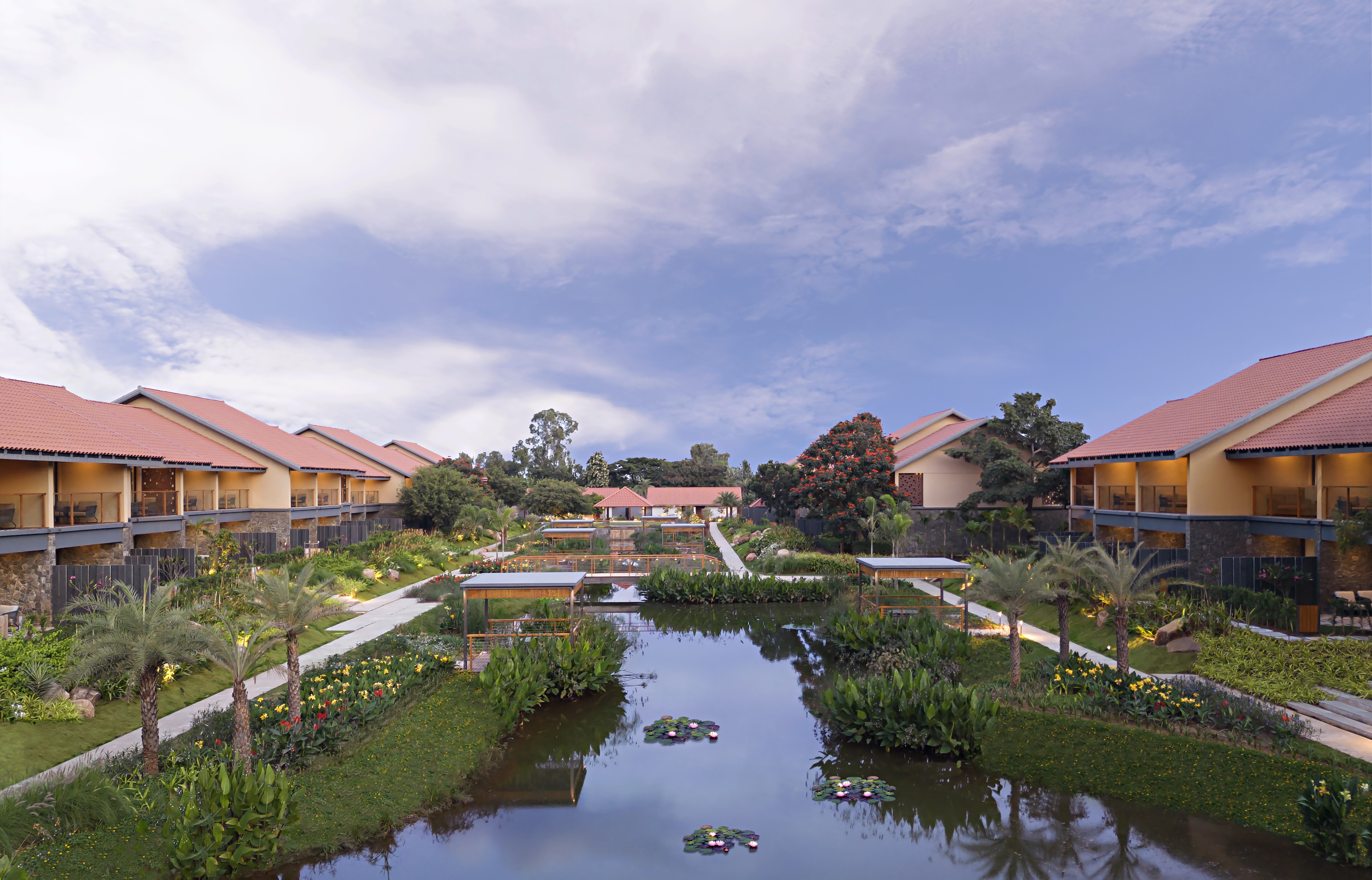 A creek surrounded by greenery runs between buildings of the hotel