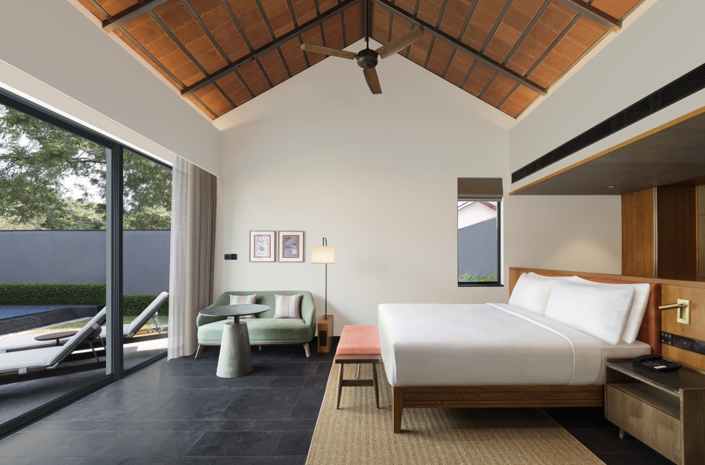 A room with bed and couch looking out at a pool