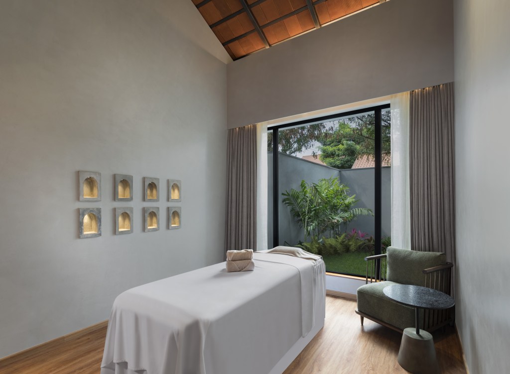 A massage table in front of a large window looking out at greenery