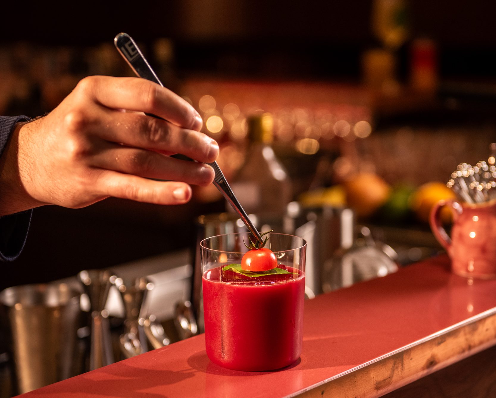 A bartender adding garnish to a cocktail