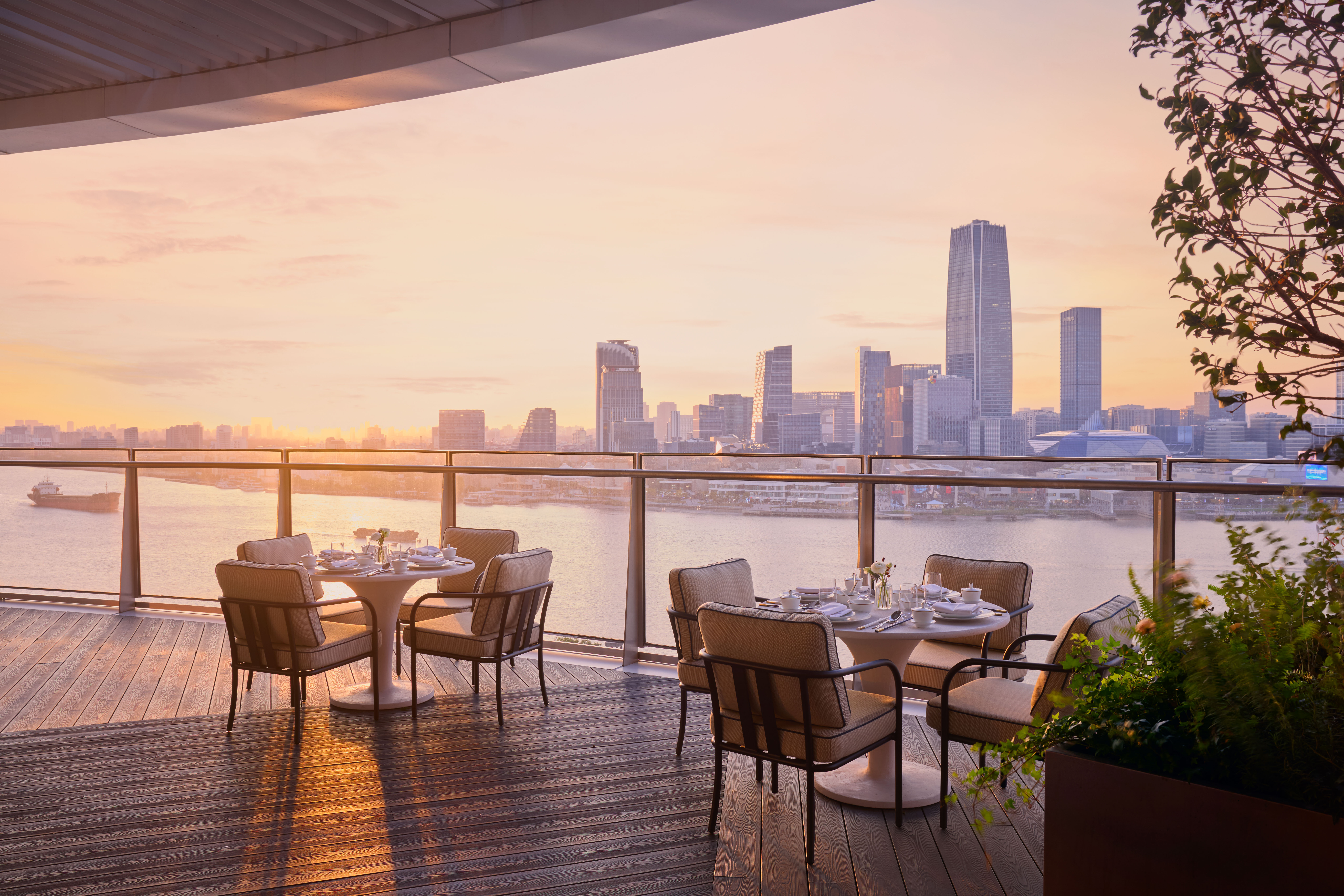 two tables on a terrace looking out over the water and the city at sunset