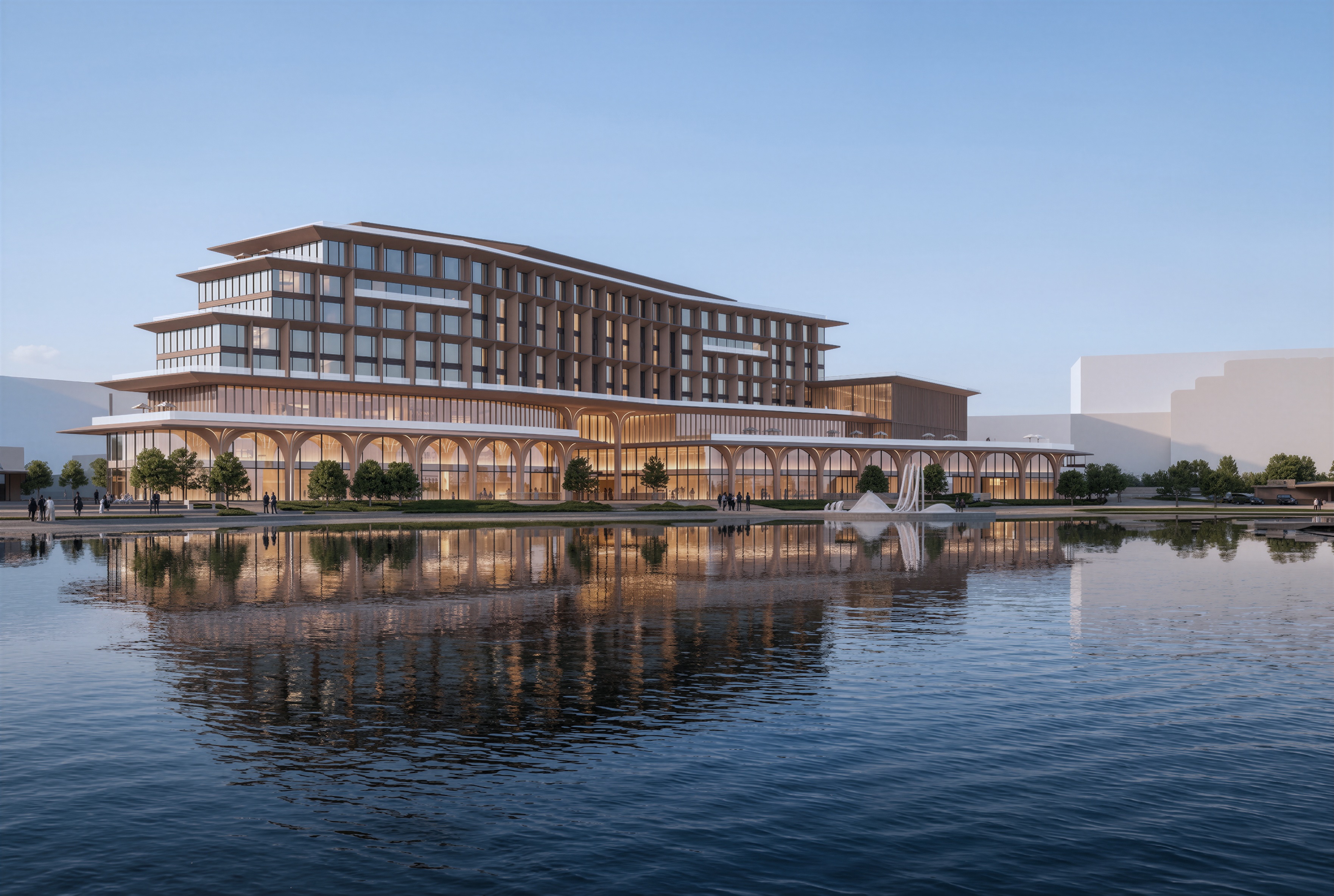 Modern multi-story building with large glass windows and arches, reflected in a calm body of water under a clear sky.