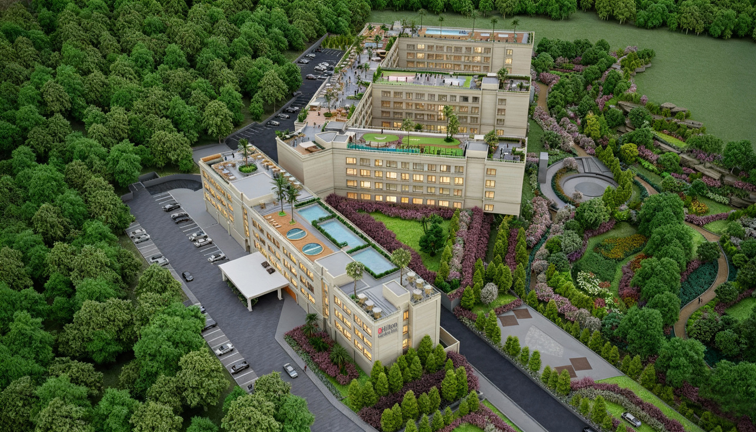 A large Hilton Garden Inn hotel surrounded by dense green trees and landscaped gardens with rooftop pools and terraces.