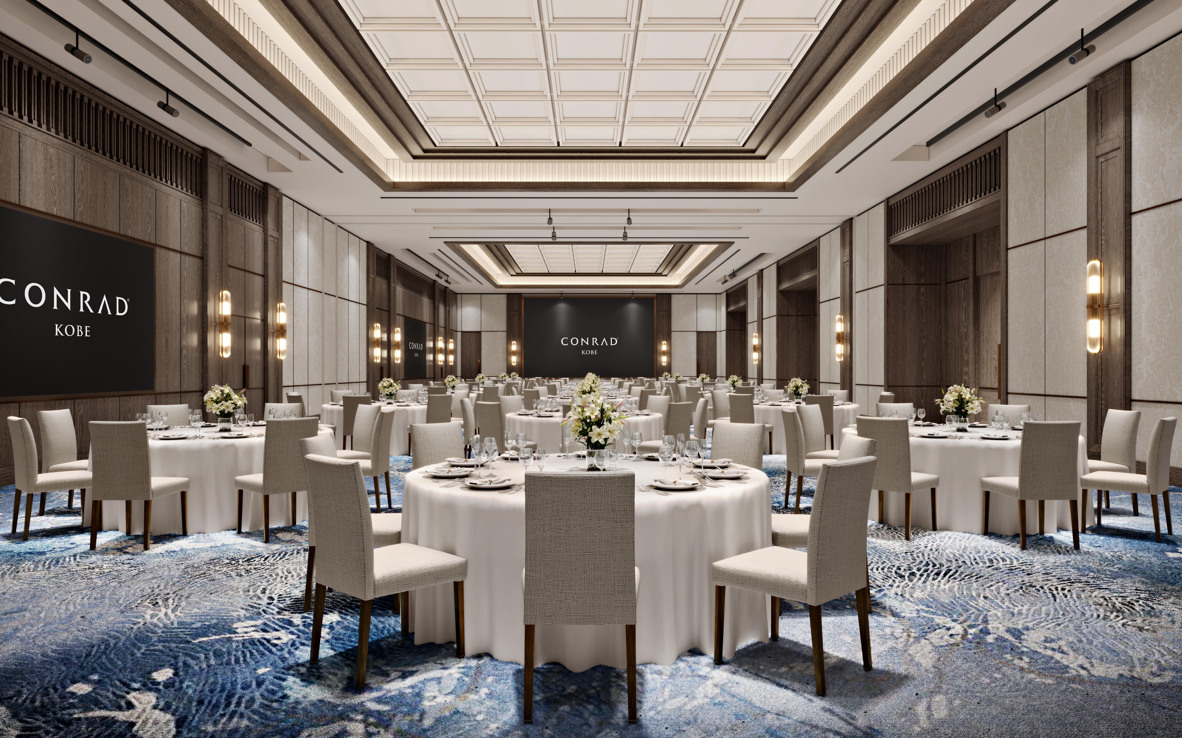 Elegant banquet hall with round tables set for dining, featuring white tablecloths, floral centerpieces, and neutral-toned chairs at the Conrad Kobe.