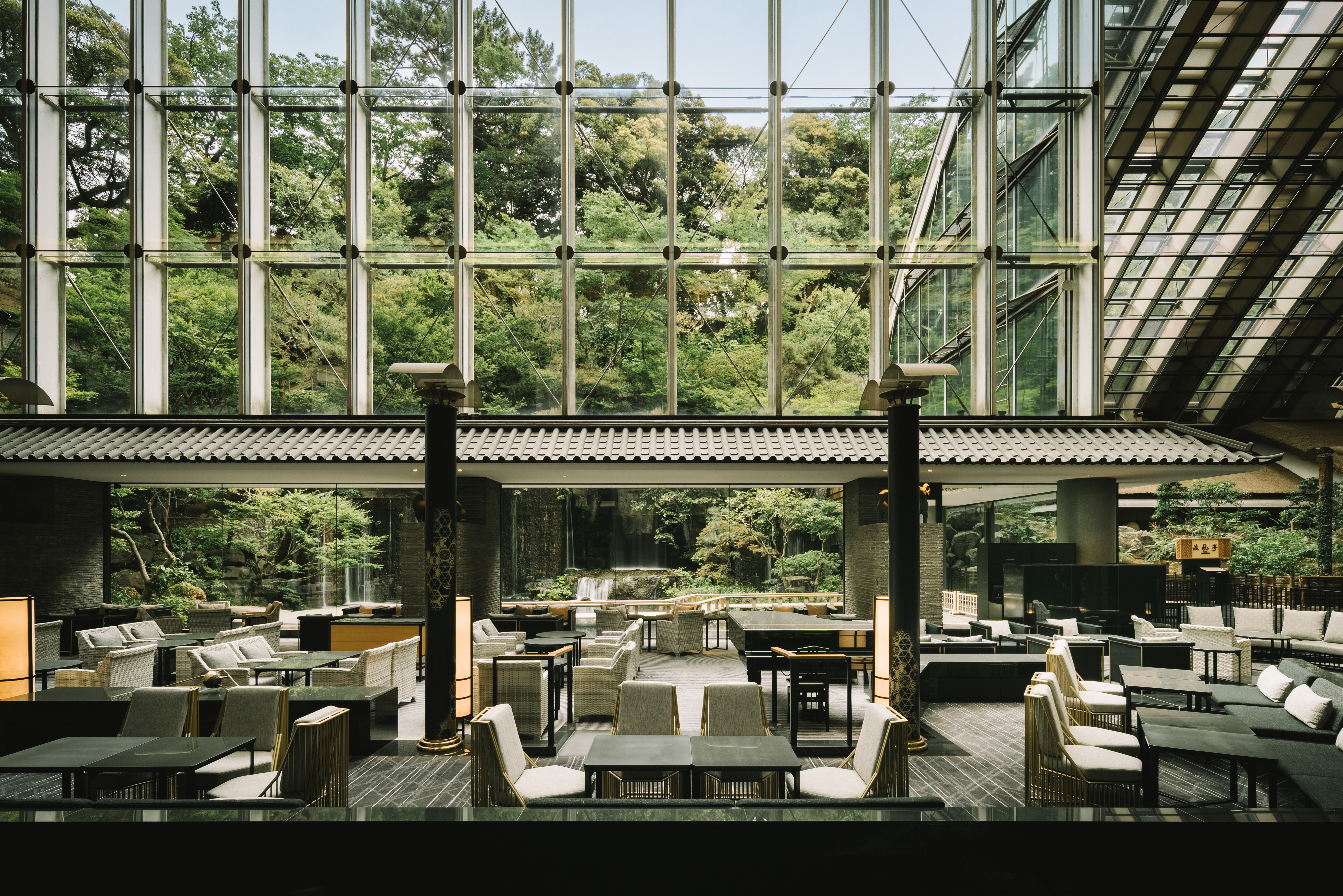 Spacious modern lounge with glass walls overlooking a lush green garden.