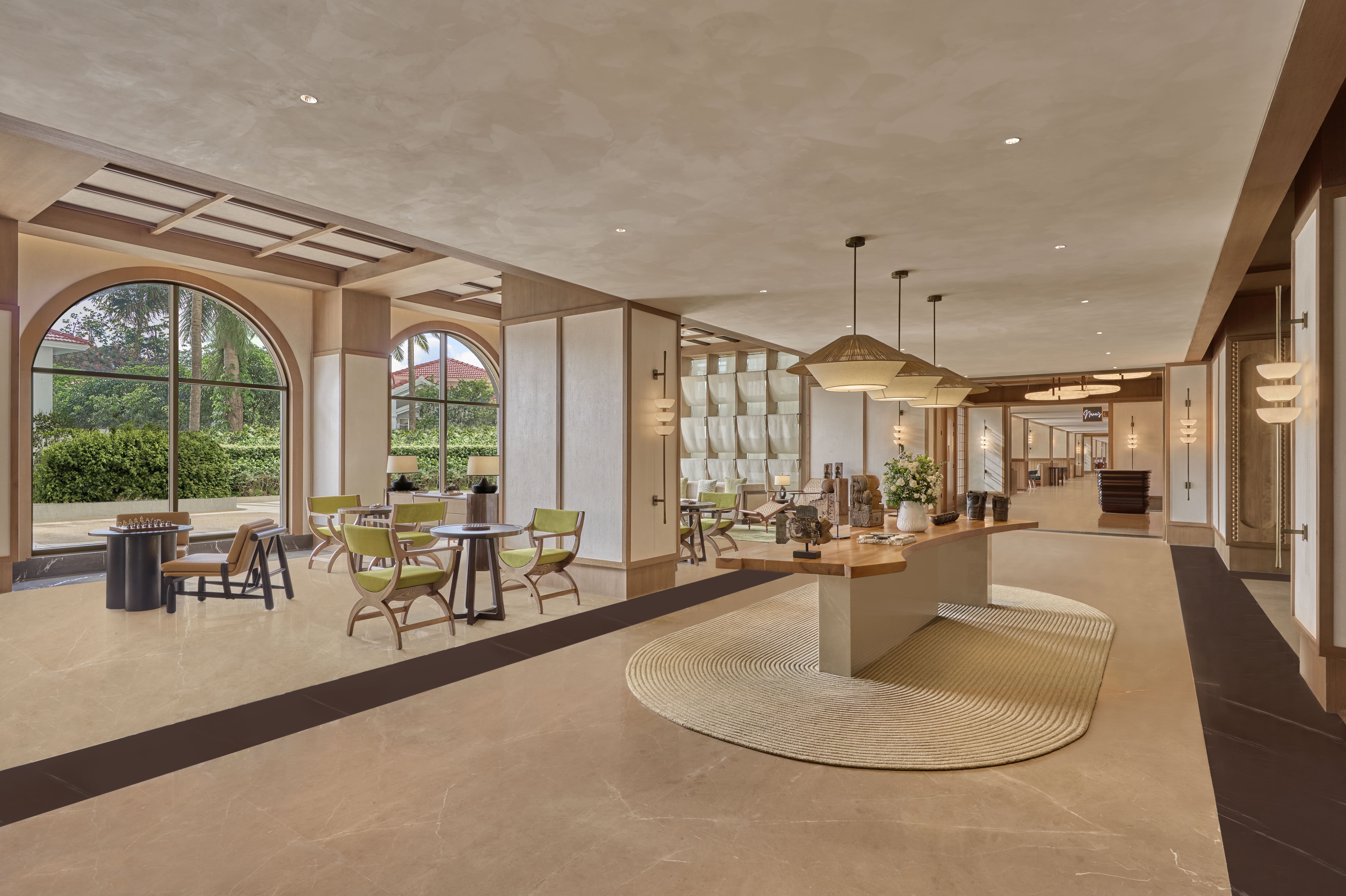 Spacious modern lobby at the Slohh by Roach, Curio Collection by Hilton with large arched windows, green chairs around small tables.