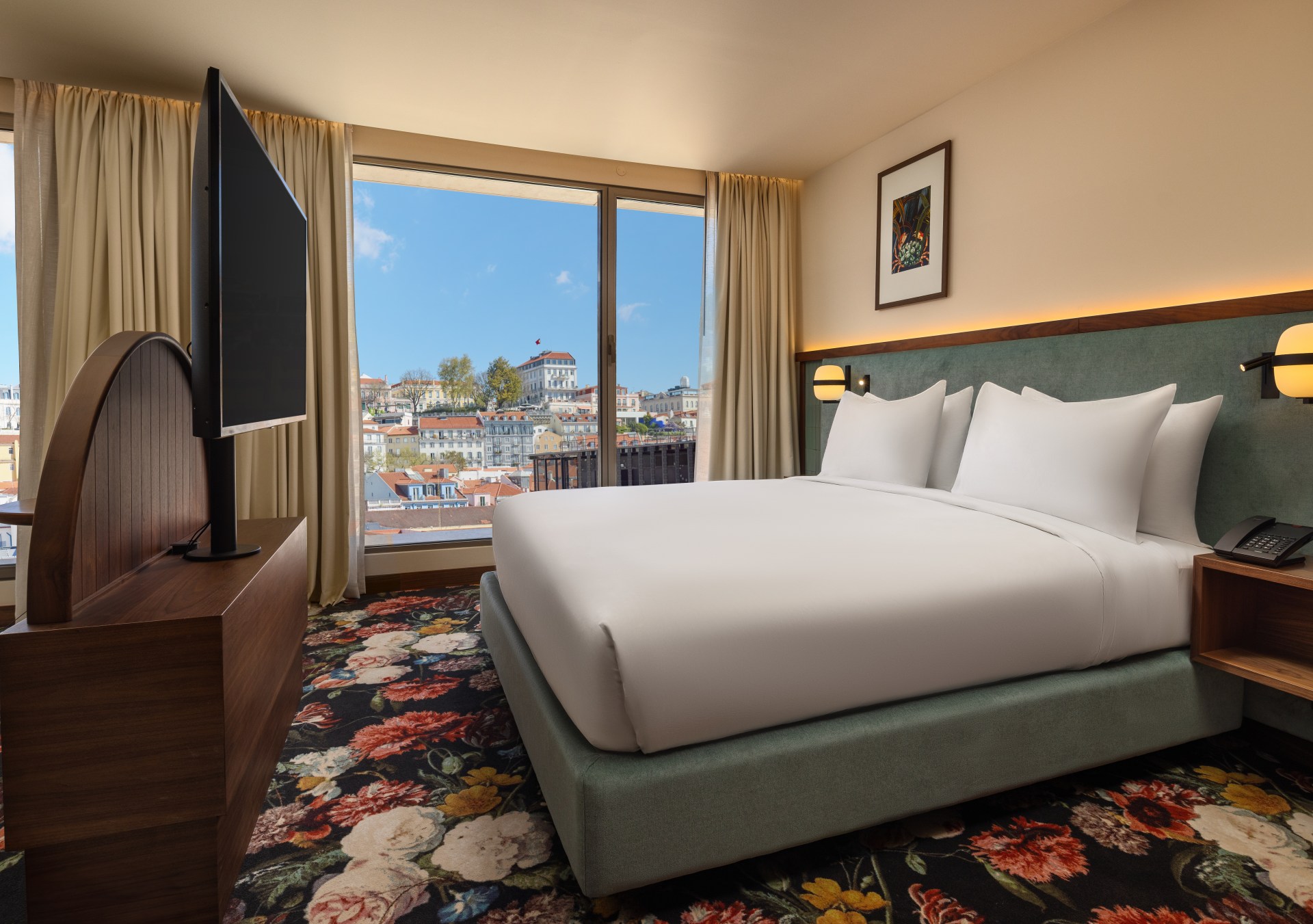 guest room with bed, tv, colorful flower carpet and window looking out at Lisbon - DUO Hotel Lisbon, Curio Collection by Hilton