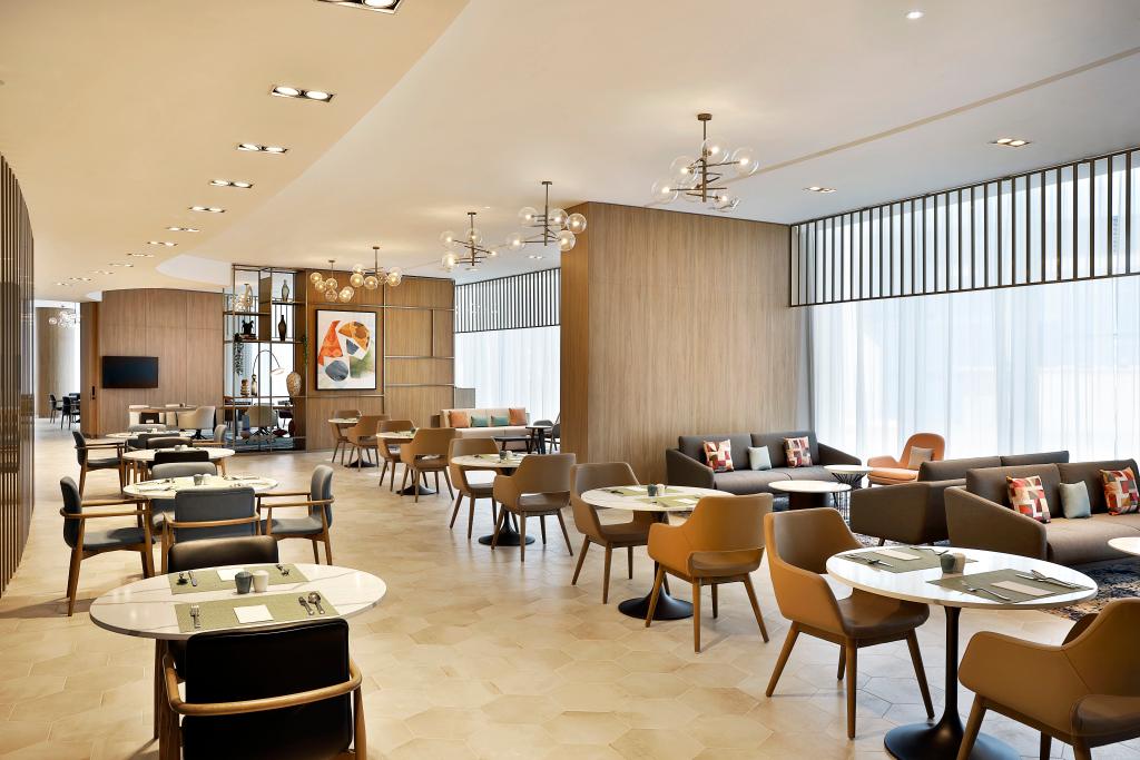 Hilton Garden Inn Dubai Business Bay - Together&amp;Co - restaurant with lots of seating, light wood walls and large windows