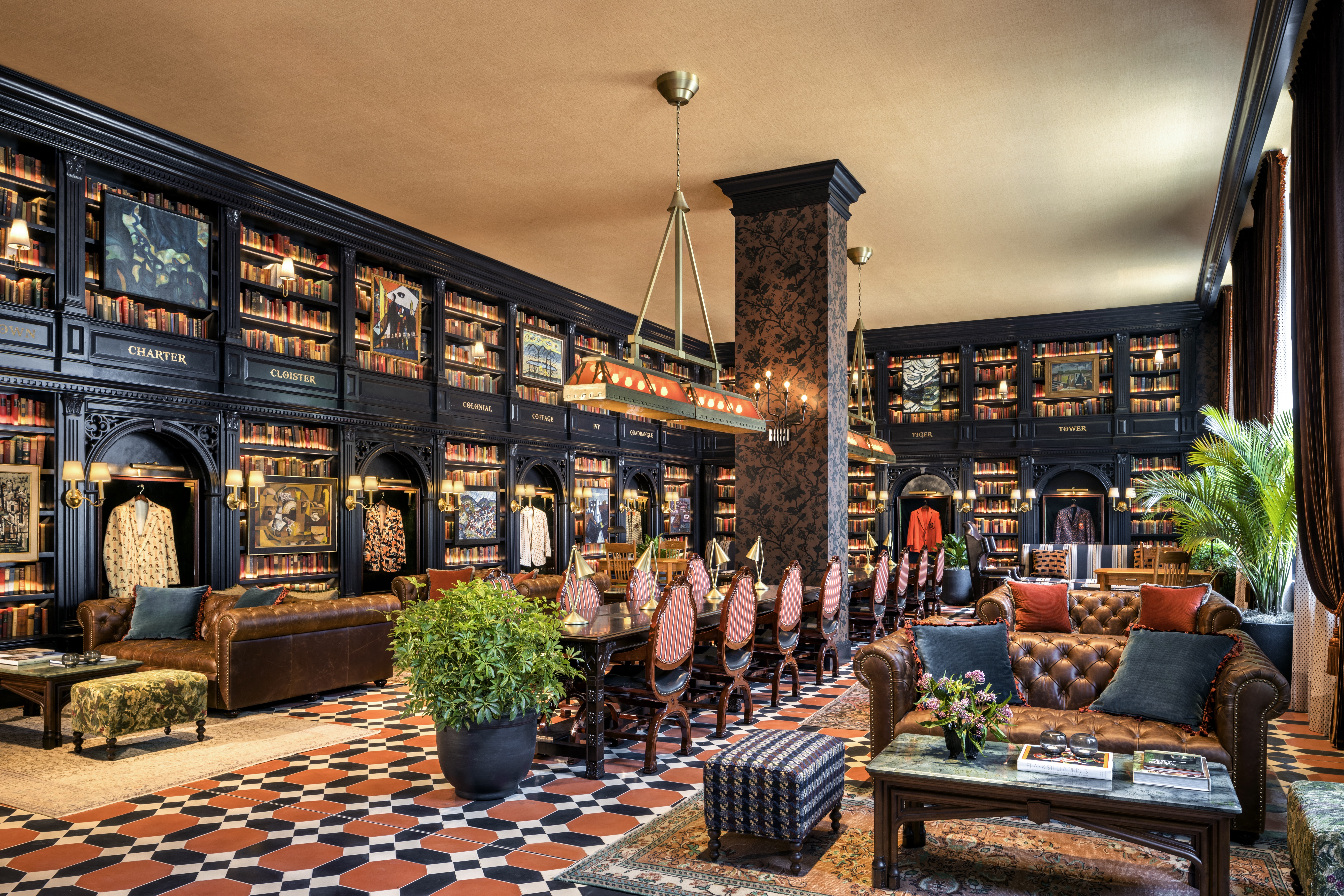 Graduate Princeton Lobby, book shelves, couches, leather arm chair, floral ottoman, arts on walls, plants, tables, coffee tables suits hung as decoration