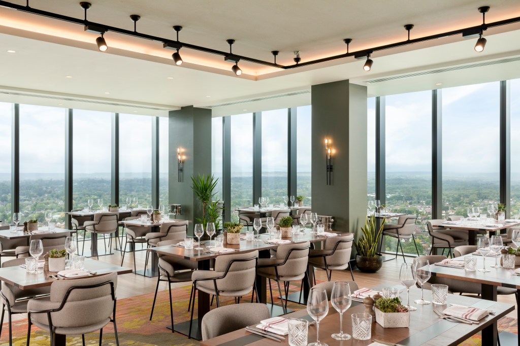 Hilton Woking - OXBO restaurant dining area, tables, chairs, wine glasses, place settings, windows with view of surrounding area