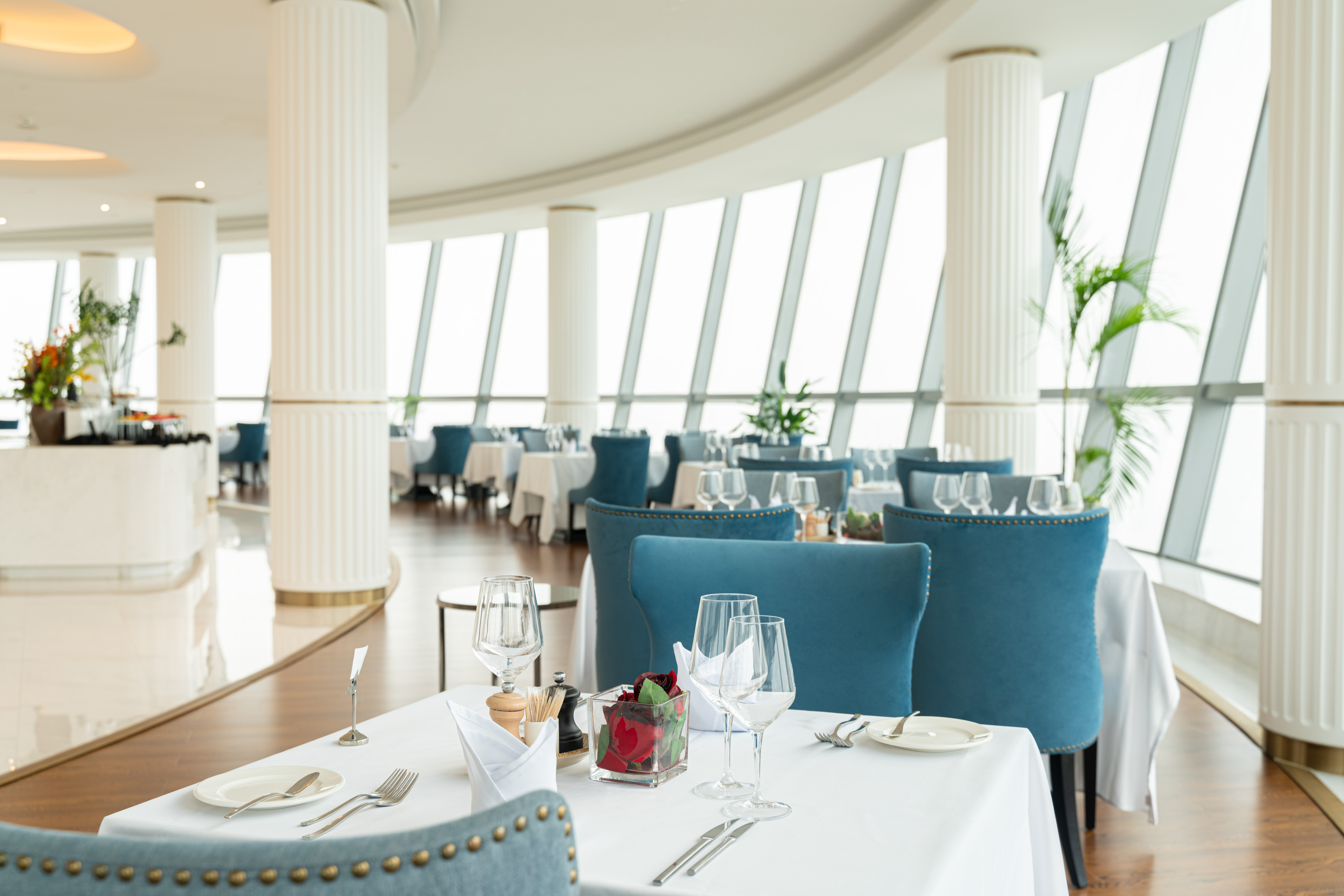 Hilton Brazzaville Les Tours Jumelles Hotel &amp; Residences, Restaurant, fine dining, white columns, blue chairs, potted plants, stem ware, forks, knives, spoon, plate, salt and pepper shaker