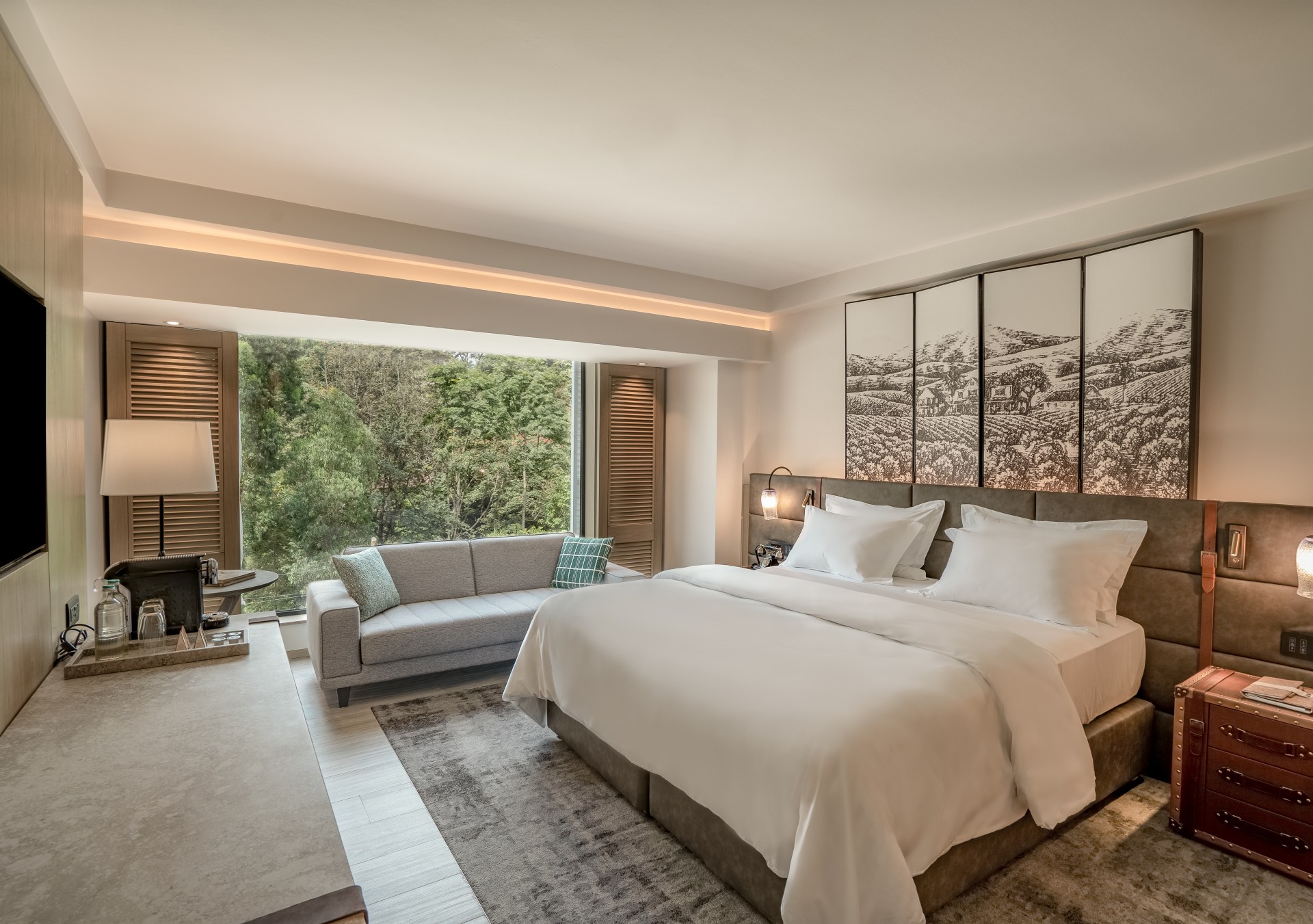 Kwetu Nairobi, Curio Collection by Hilton, King Deluxe Room, Guest Room, grey couch, indoor shutters, area rug, white pillows, white bedding, black and white hanging art