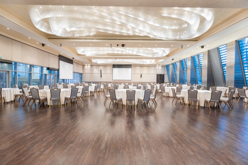 Onyx Hall at the Convention Center Ballrooms, large ball room with tables and chairs, wood floor and projector screens