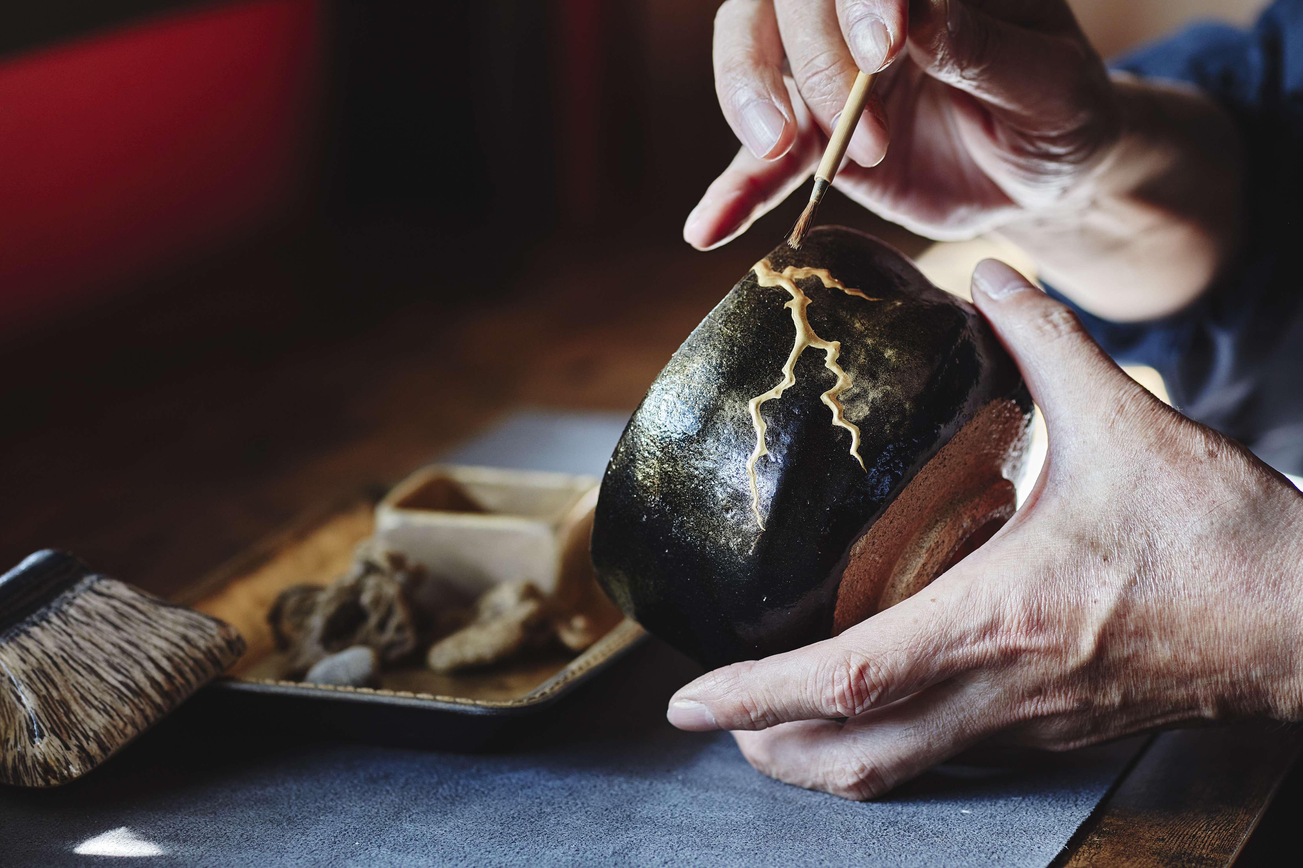 ROKU KYOTO, LXR Hotels &amp; Resorts, Kintsugi Experience, person holding brush and painting ceramic piece