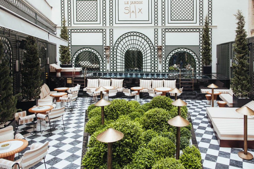 Sax Paris, LXR Hotels & Resorts - The Garden, view of garden area with orange and white striped tables and chairs, chess board flooring and pool in the background