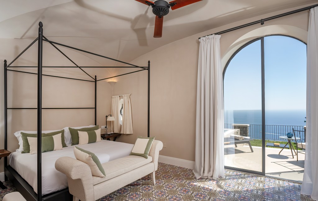 Furore Grand Hotel, an SLH Hotel Signature Suite Pool with a canopy bed atop tiled floor with a walkout arched door leading you to outdoor seating area with a pool