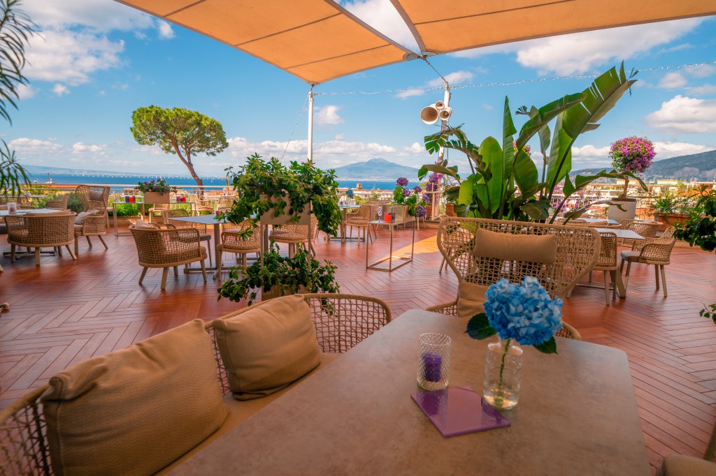 Hilton Sorrento Palace La Terrazza Lounge Bar outdoor seating area with potted trees and plants overlooking the water