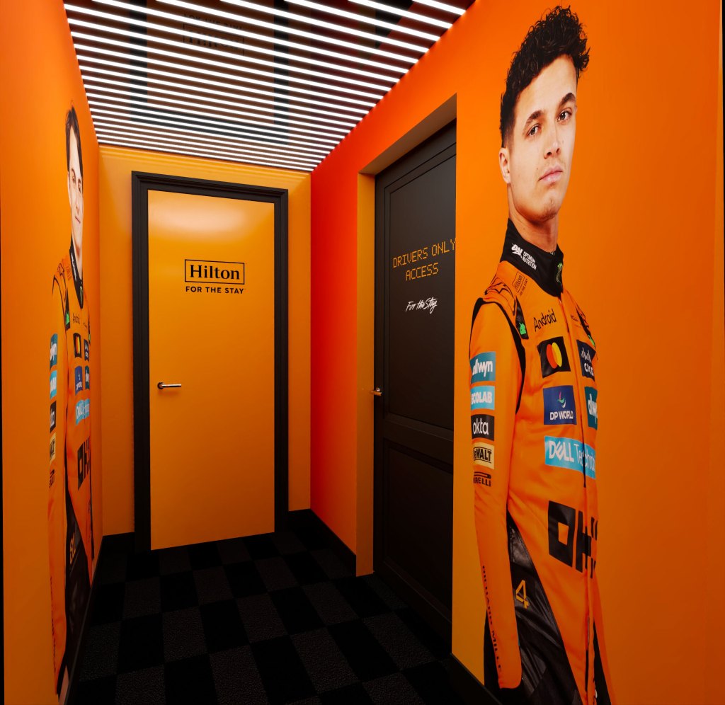 Stay Like McLaren Racing Suite at The Trafalgar St. James London, Curio Collection by Hilton - Entryway with Papaya door and walls and large murals of Oscar Piastri and Lando Norris