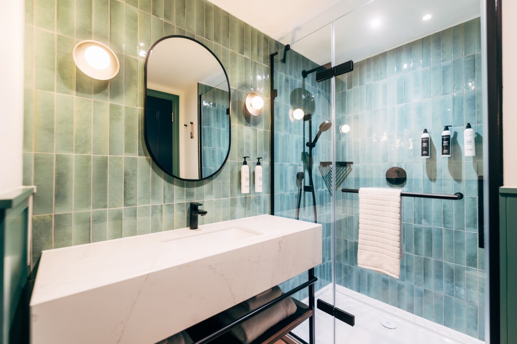 Guest Room Bathroom with light green tile, sink and and large open shower with glass wall at The Marcus Portrush, Tapestry Collection by Hilton