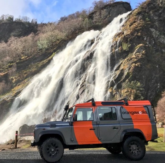 Conrad Dublin - Explore Wicklow in a Land Rover, grey and orange Land Rover in front of a waterfall